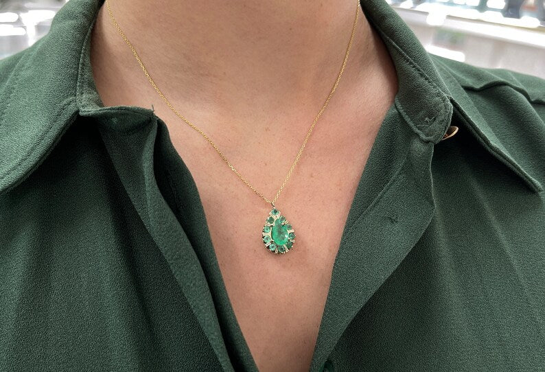 14K gold Colombian emerald pendant necklace with pear and round cut gemstones, featuring prong setting and multi-gemstone design.