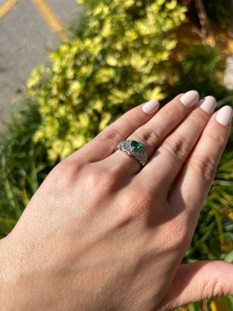 14K Colombian Emerald and diamond cluster statement ring with a 0.90tcw trilliant cut emerald in a detailed ring setting.