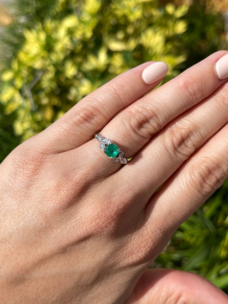 14K gold Zambian emerald and diamond floral ring featuring round cut diamonds and vibrant emeralds.