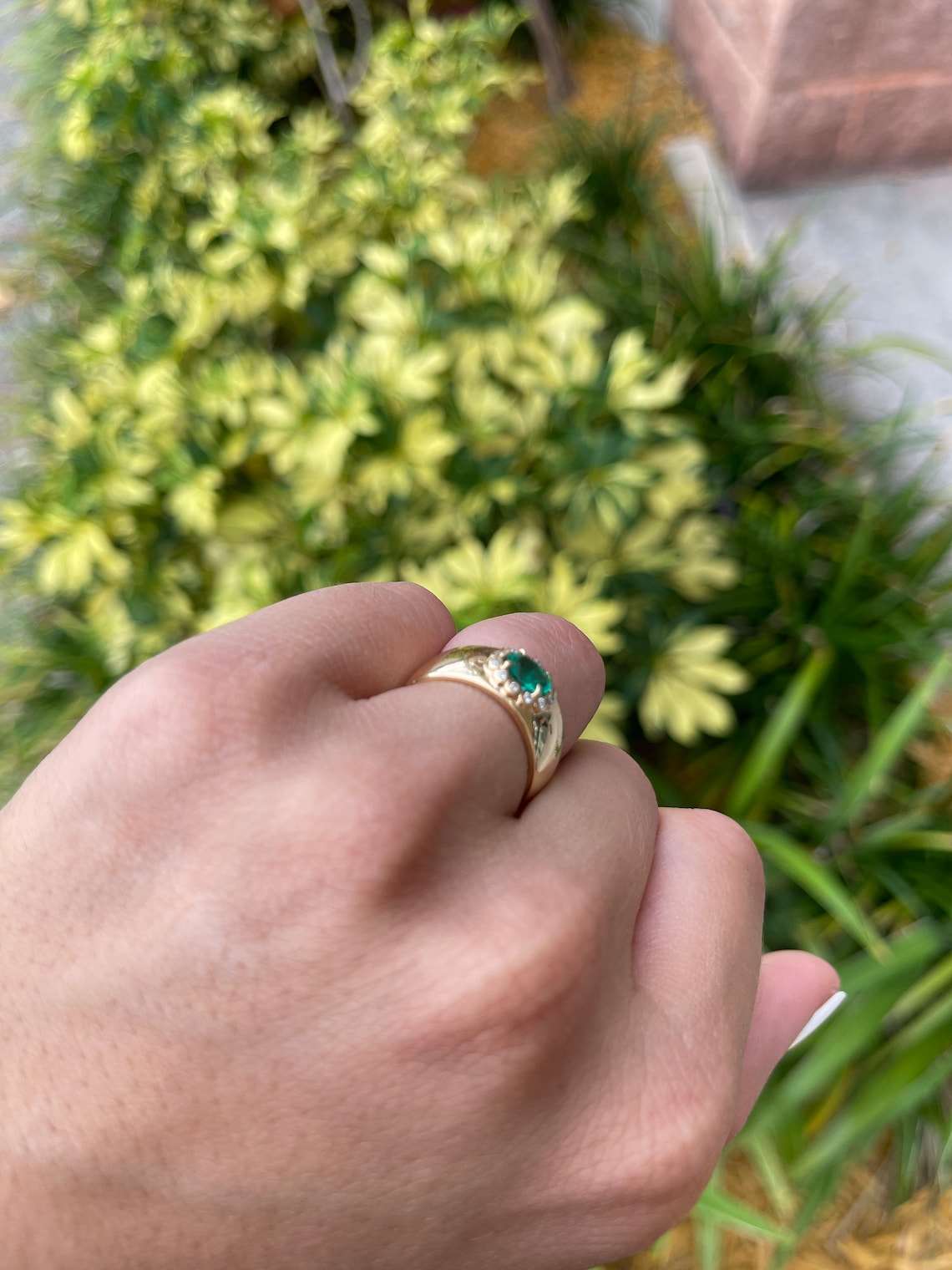 Oval cut Colombian emerald ring with diamond halo accents in 14K gold, showcasing a vibrant green gemstone and intricate design.
