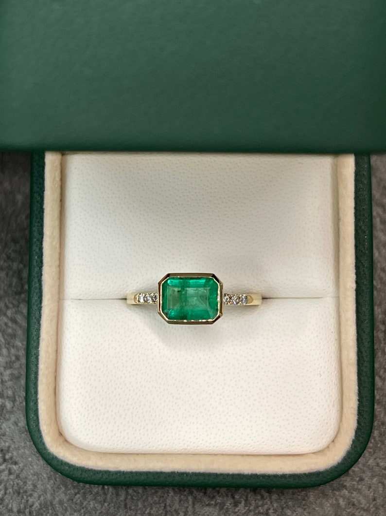 Colombian Emerald 14K gold ring featuring a 1.15tcw emerald cut emerald with diamond accents, bezel setting, elegant jewelry design