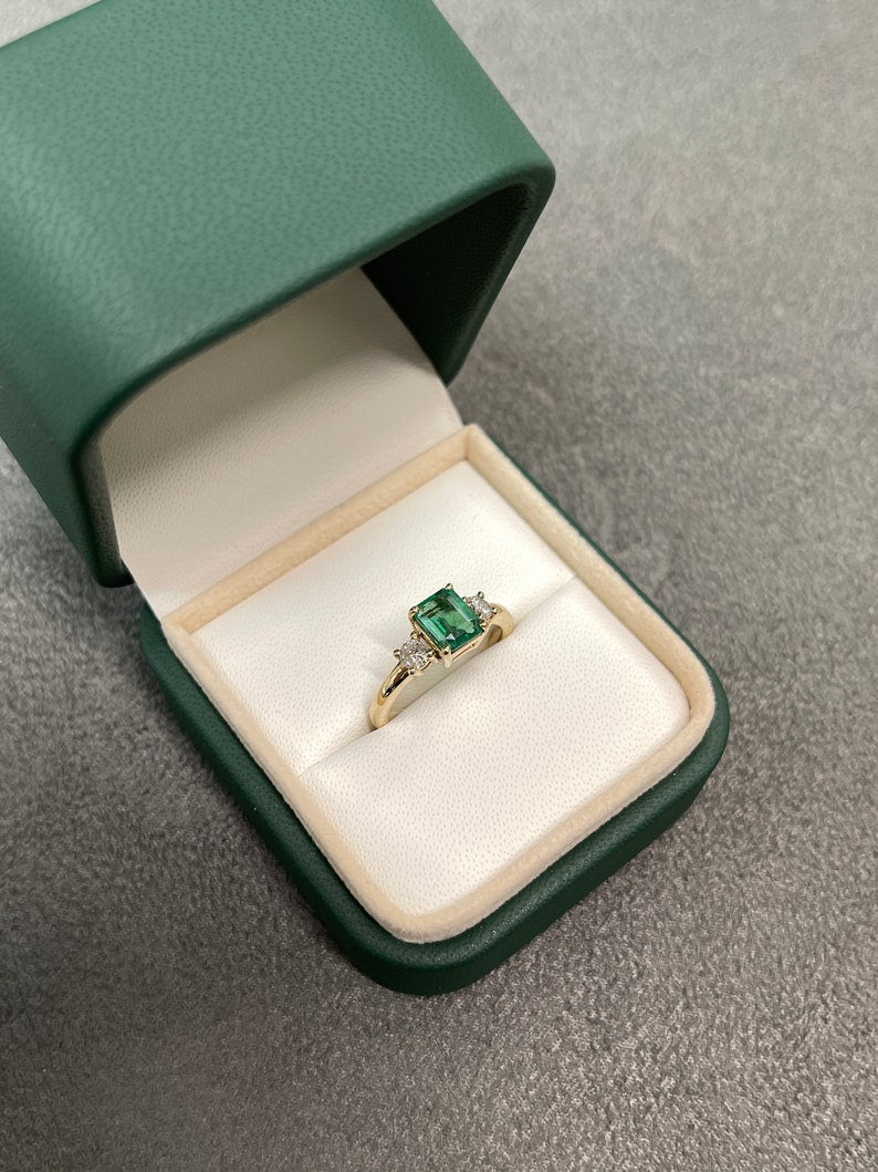 Colombian Emerald 14K gold three-stone ring with round diamonds and emerald accents, showcasing a transparent, elegant design.