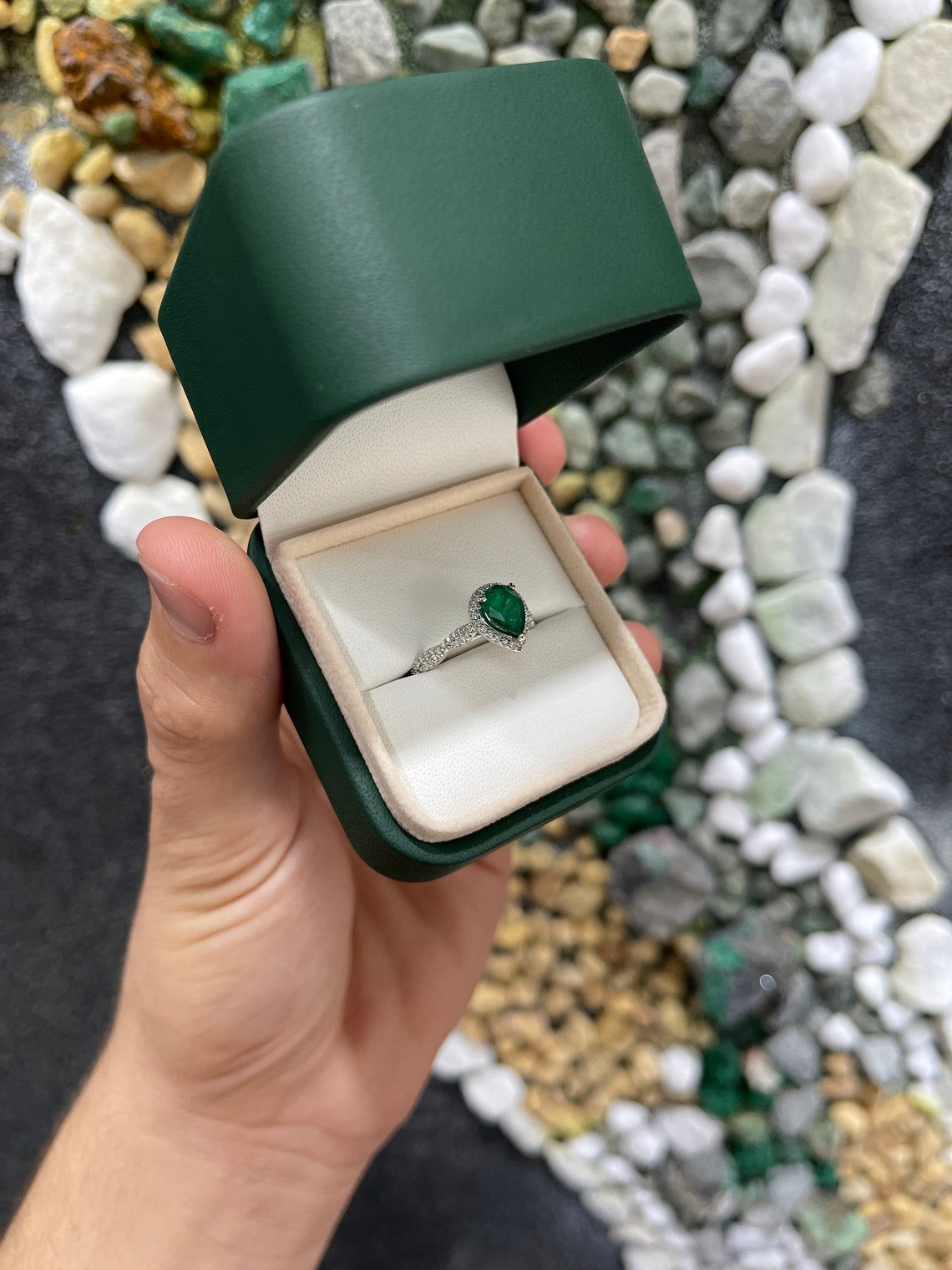 Natural emerald pear-shaped engagement ring with diamond halo in 14K gold, featuring Colombian Emerald branding.