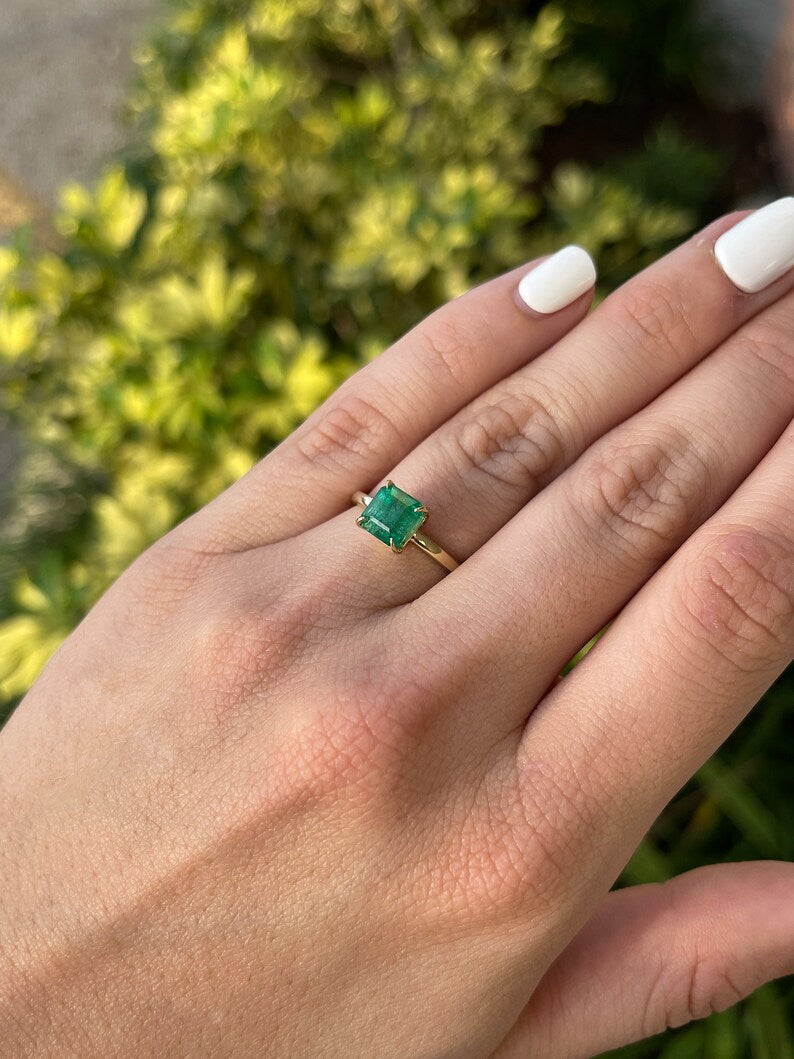14K gold solitaire engagement ring featuring a 2.65ct emerald cut Colombian Emerald gemstone, classic and elegant design.