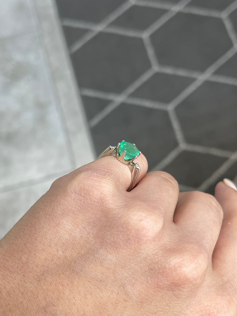 14K Colombian Emerald and diamond accent three-stone gold ring featuring a round cut emerald, showcasing elegant jewelry craftsmanship.