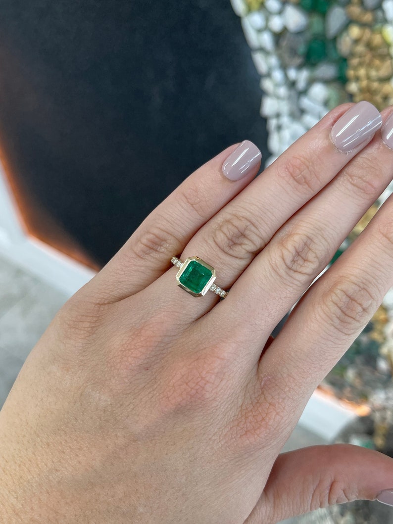 14K gold square emerald and diamond accent solitaire ring featuring Asscher cut emerald and bezel setting, designed for right hand wear.