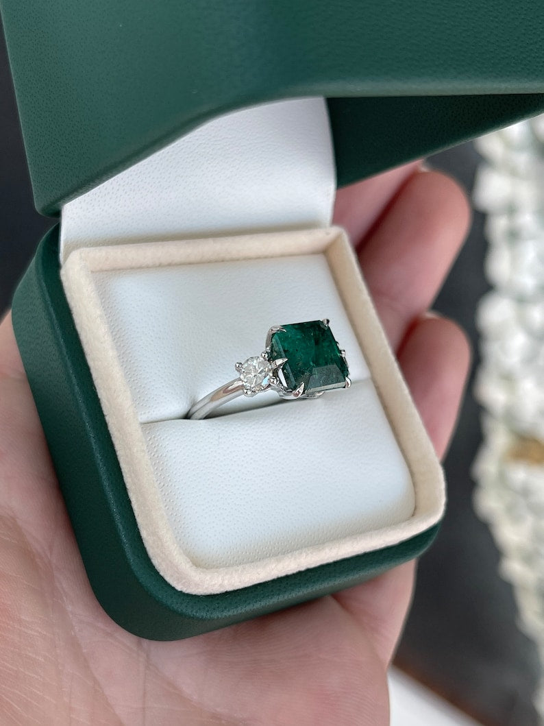 14K gold 3-stone engagement ring with intense dark green emerald and round diamonds, featuring Asscher cut emeralds.