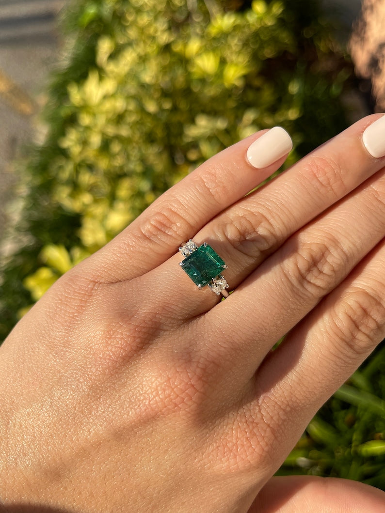 14K gold 4.90tcw dark green emerald and diamond 3-stone engagement ring with asscher cut emerald and round diamonds.
