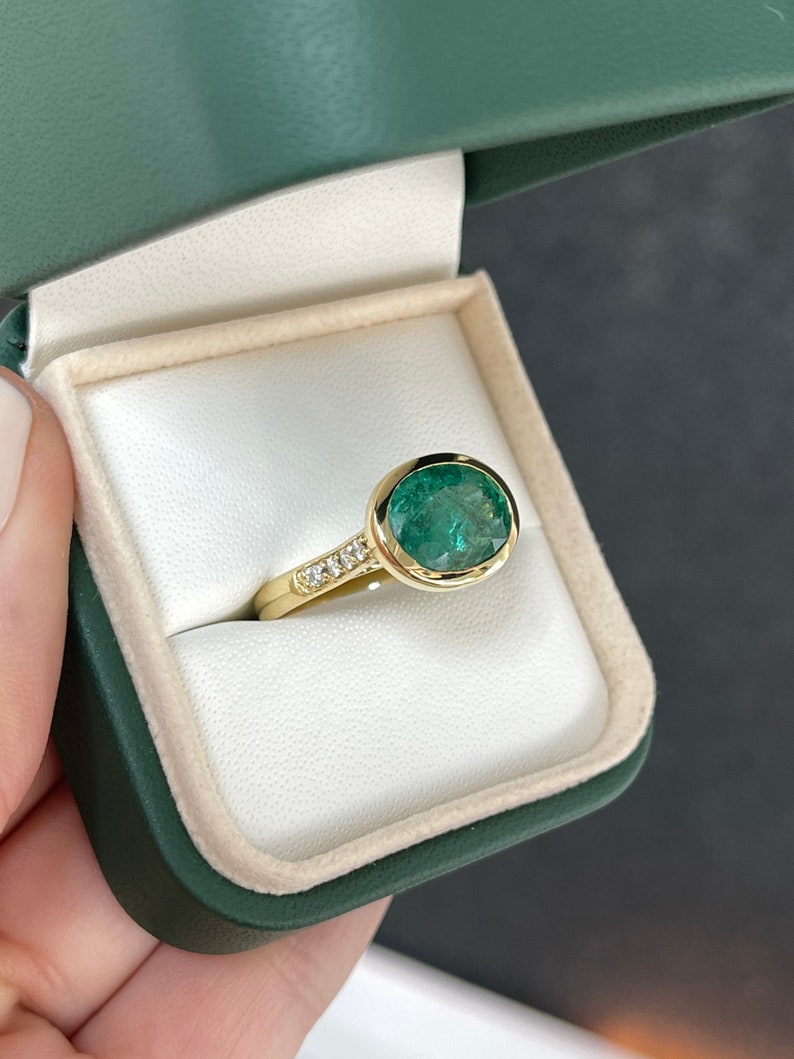 18K gold ring featuring a 5.66ct dark green oval cut bezel emerald with diamond accents on the shank, Colombian Emerald brand