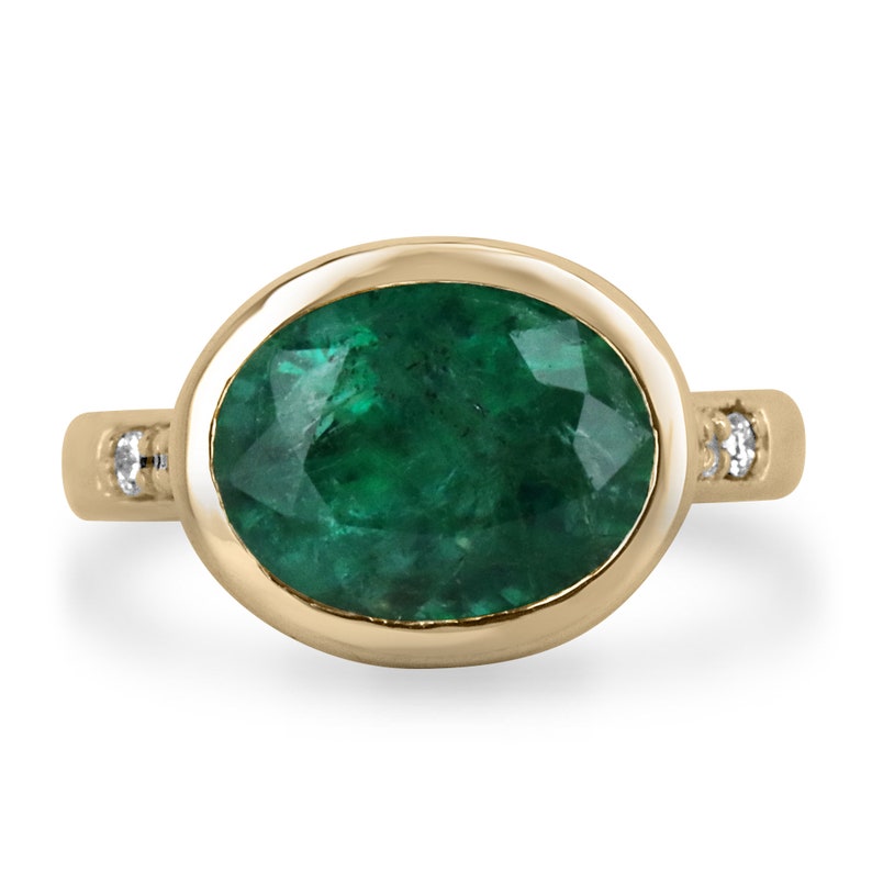 18K gold ring featuring 5.66 carats of dark green emerald in an oval cut bezel with diamond accents by Colombian Emerald