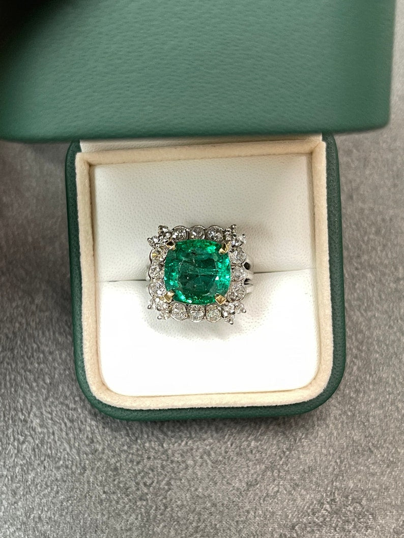 Colombian Emerald 18K gold cocktail ring with cushion-cut emerald and round diamonds, semi-transparent with intricate design.