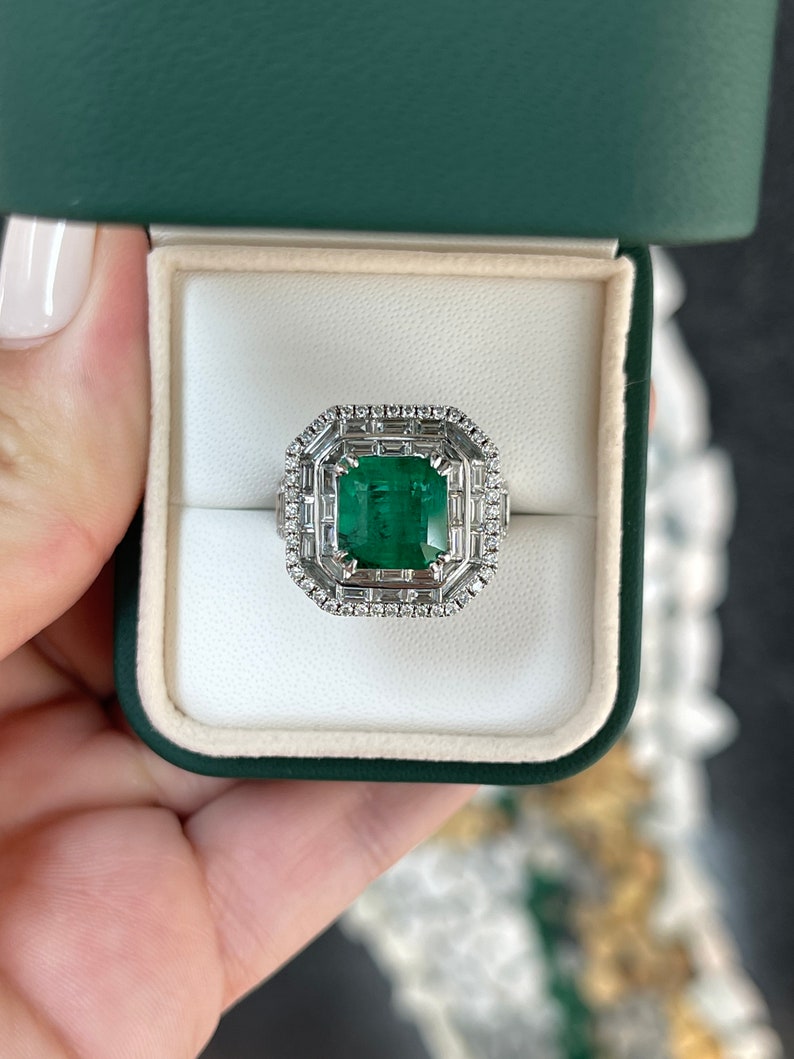 Colombian Emerald and diamond halo anniversary ring with 7.39 tcw in 18K white gold featuring a triple diamond halo design.