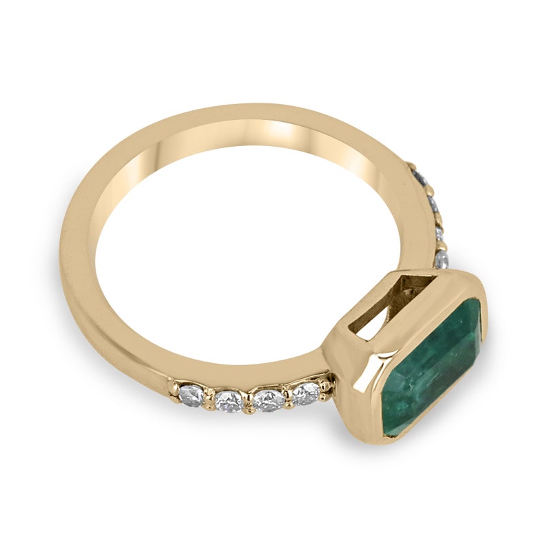 Colombian Emerald gold ring with natural emerald cut emeralds, east-west bezel setting, and diamond shank in 14K gold.