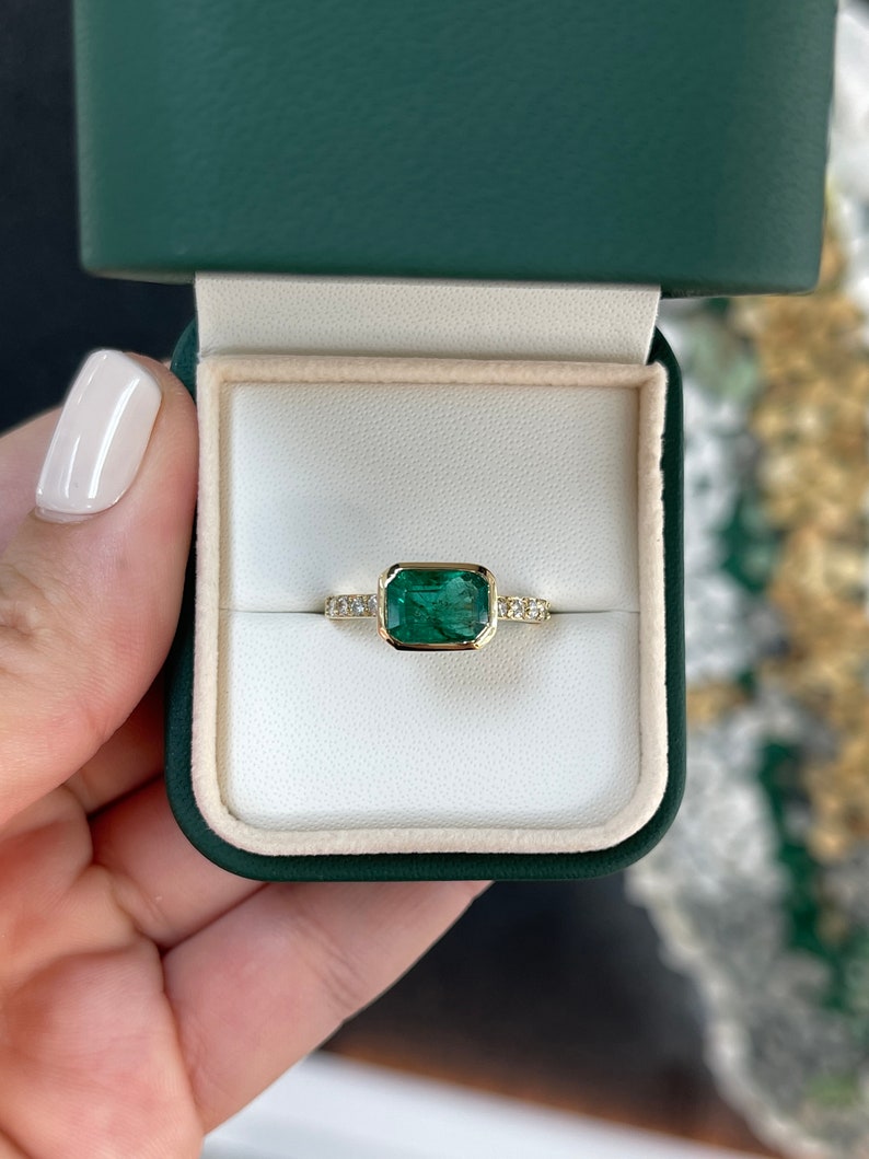 14K gold emerald cut ring with bezel set Colombian emerald and diamond shank, showcasing a luxurious and elegant design.