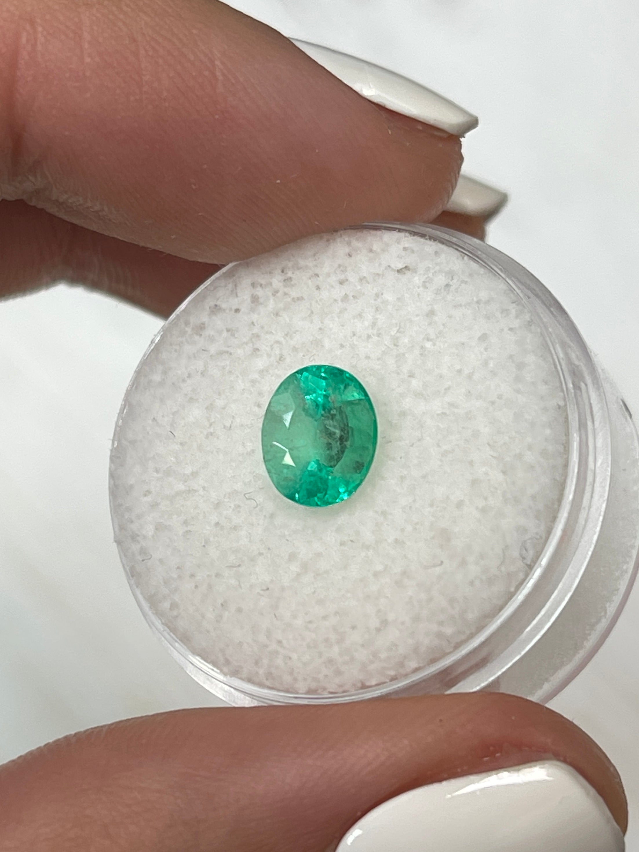 Light spring green Colombian emerald, 1.55 carat, oval cut, showcasing its vibrant color and natural clarity.