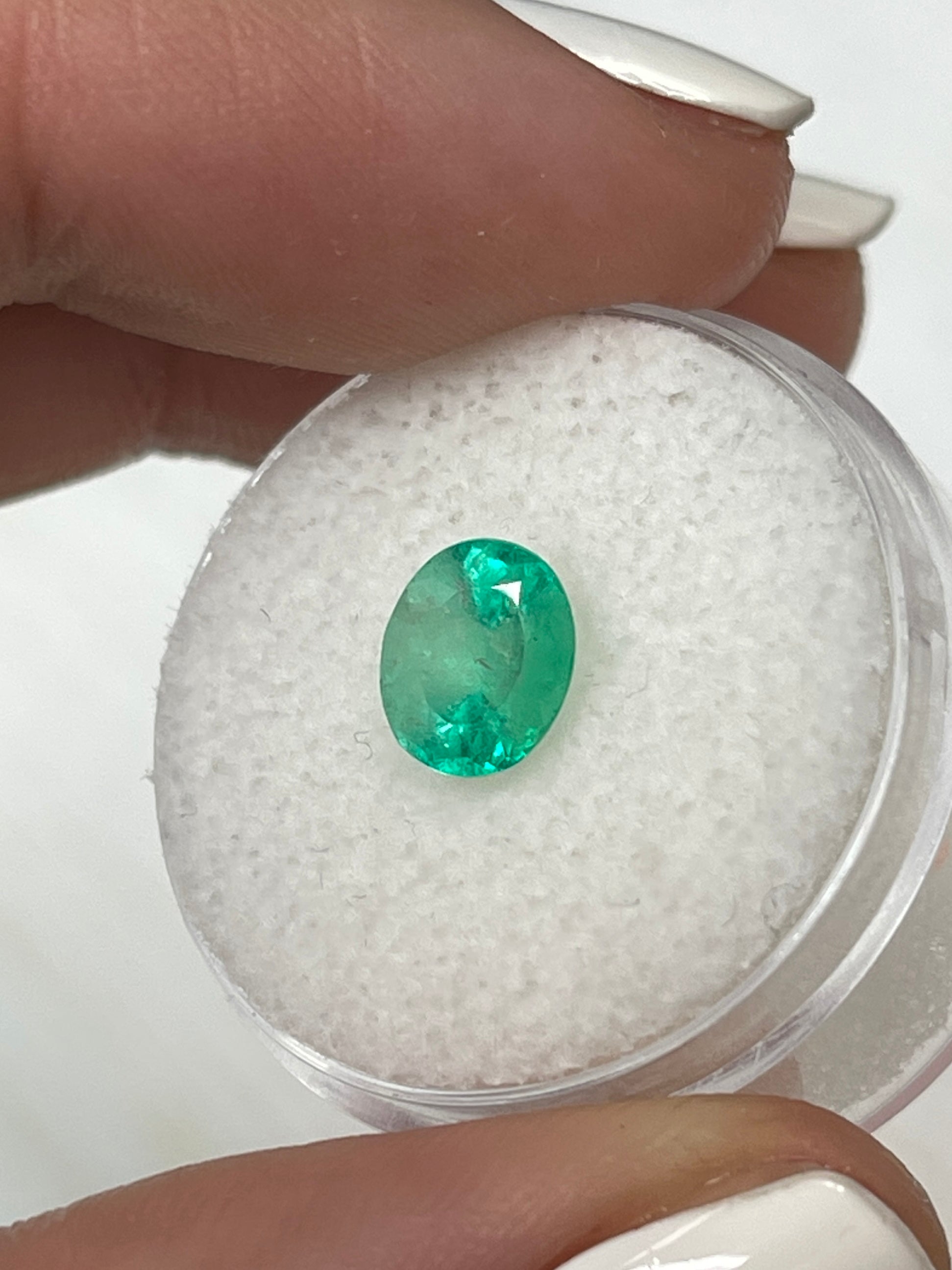 Light spring green natural Colombian emerald, 1.55 carat, oval cut, showcasing its vibrant color and clarity.