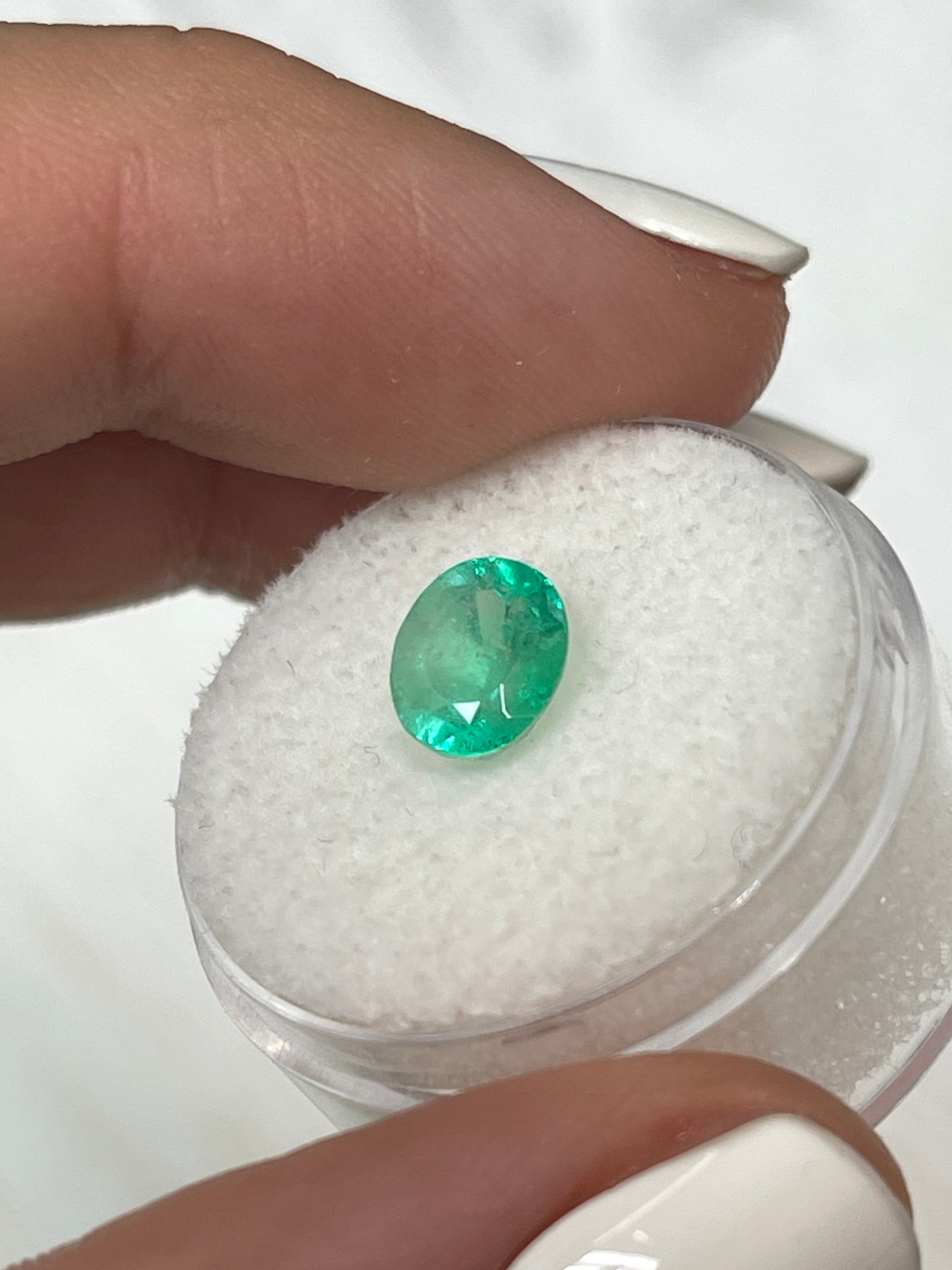 1.55 carat light spring green oval cut Colombian emerald loose gemstone from JR Colombian Emeralds on a neutral background.