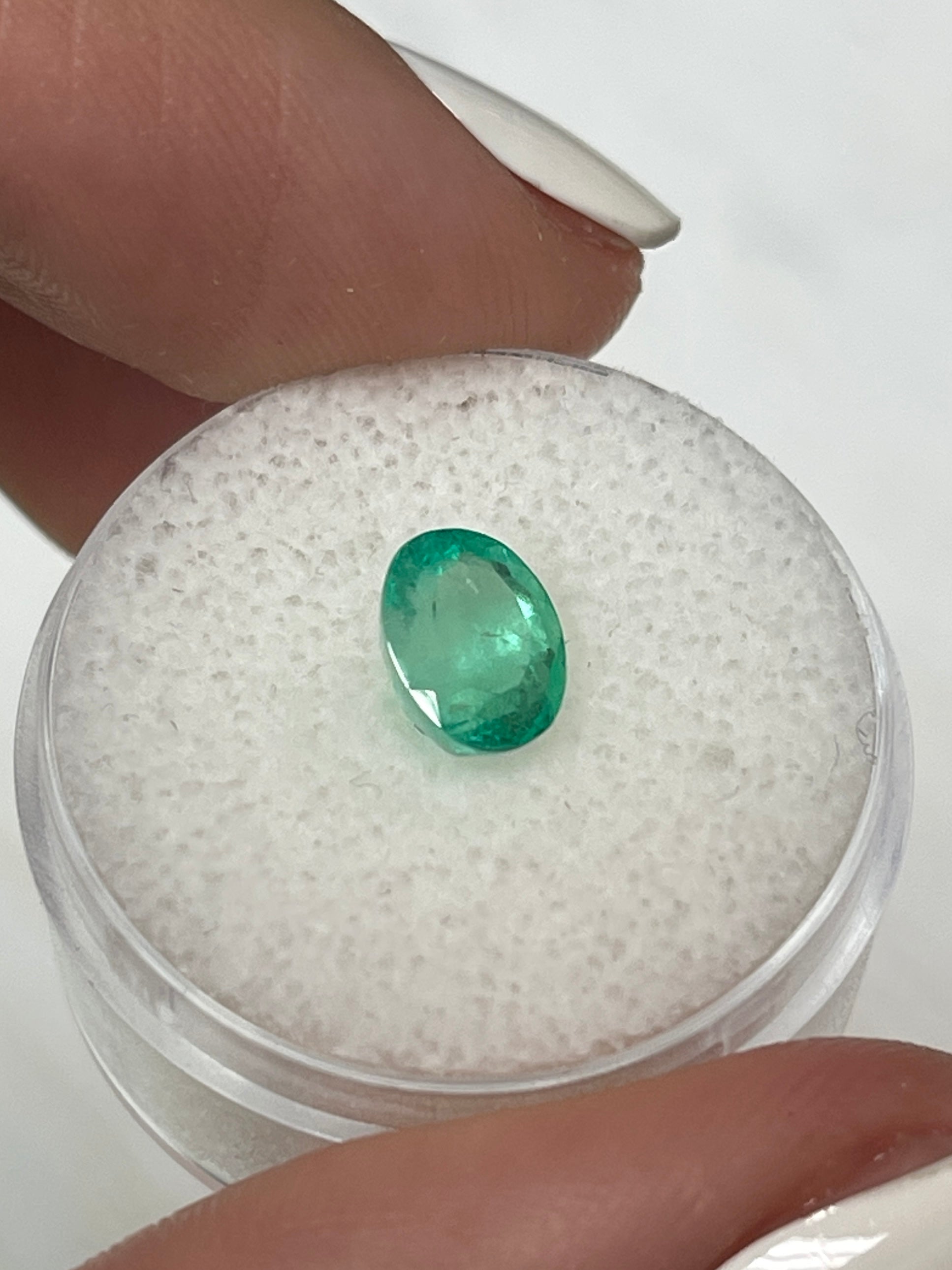 Light spring green oval cut Colombian emerald, 1.55 carats, showcasing its natural brilliance and clarity.