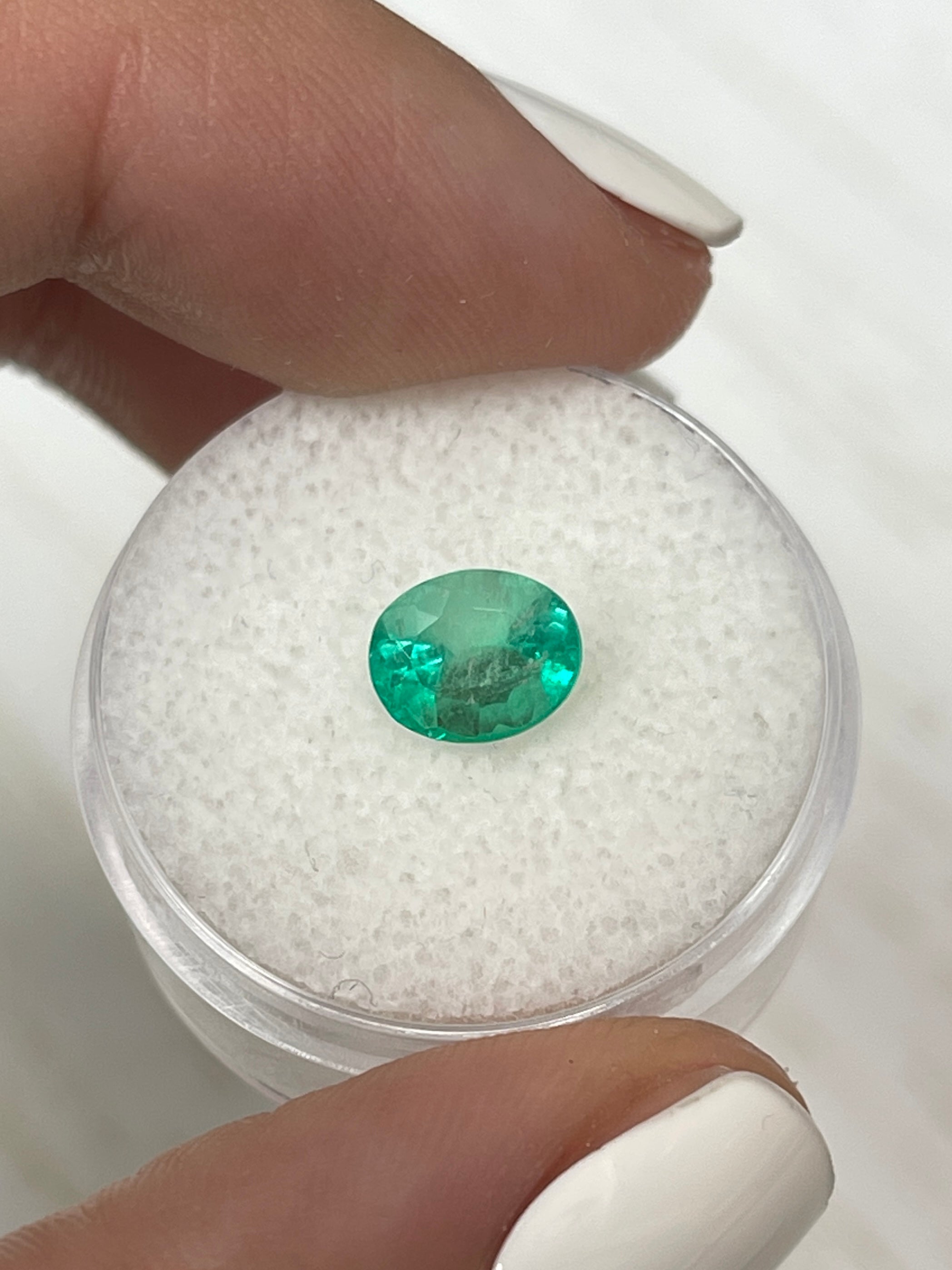 Light spring green natural Colombian emerald, 1.55 carats, oval cut, showcasing its clarity and vibrant color.
