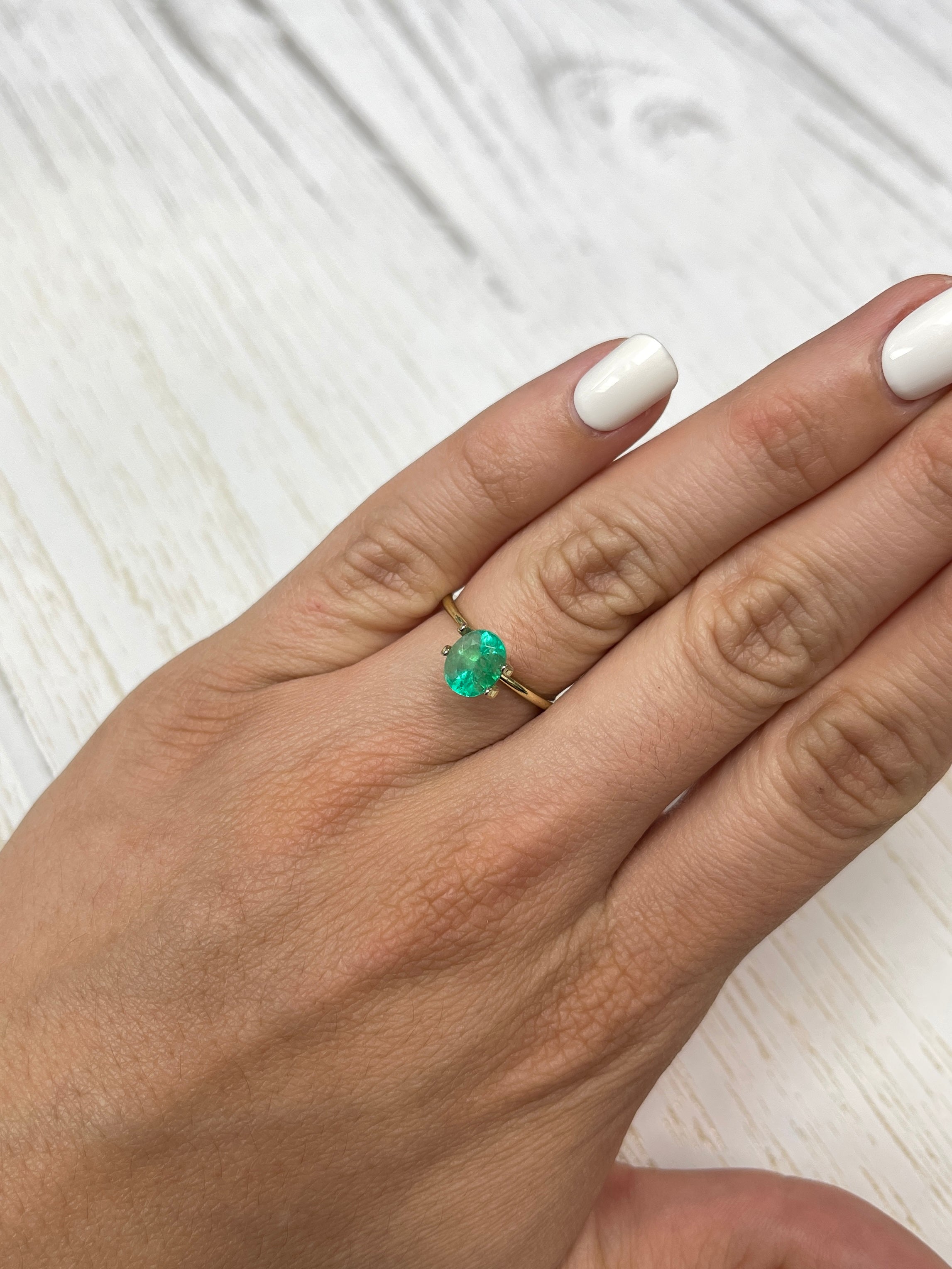 Light spring green oval cut Colombian emerald, 1.55 carats, showcasing its natural brilliance and clarity.