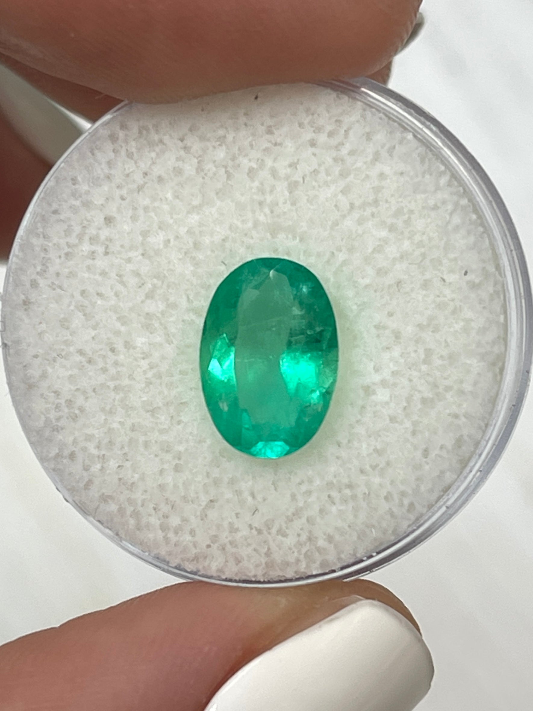 Elongated 11x8mm Colombian emerald loose gemstone with vivid apple green color and oval cut, by JR Colombian Emeralds.