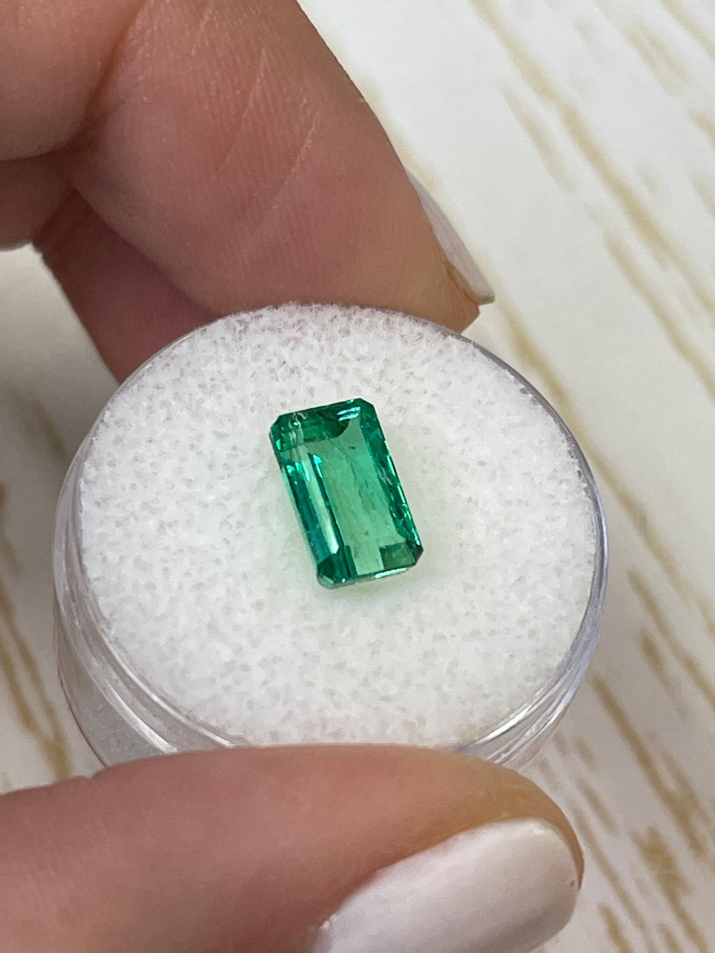 Loose 2.38 carat Muzo green Colombian emerald cut in a slender 10x6mm shape, showcasing vibrant emerald-green color and clarity.