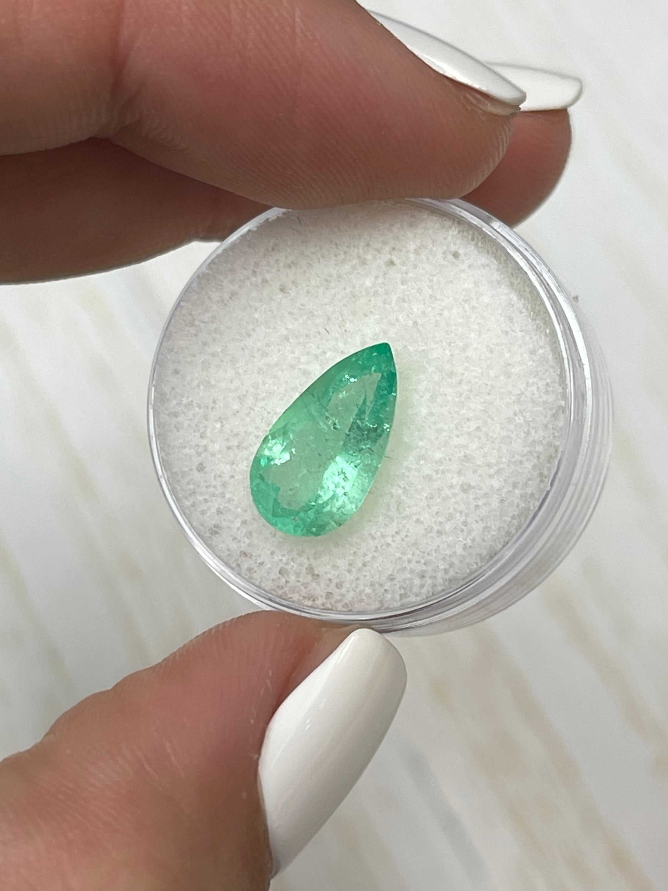 2.76 carat elongated green Colombian emerald in a pear cut, showcasing its vibrant color and clarity against a neutral background.