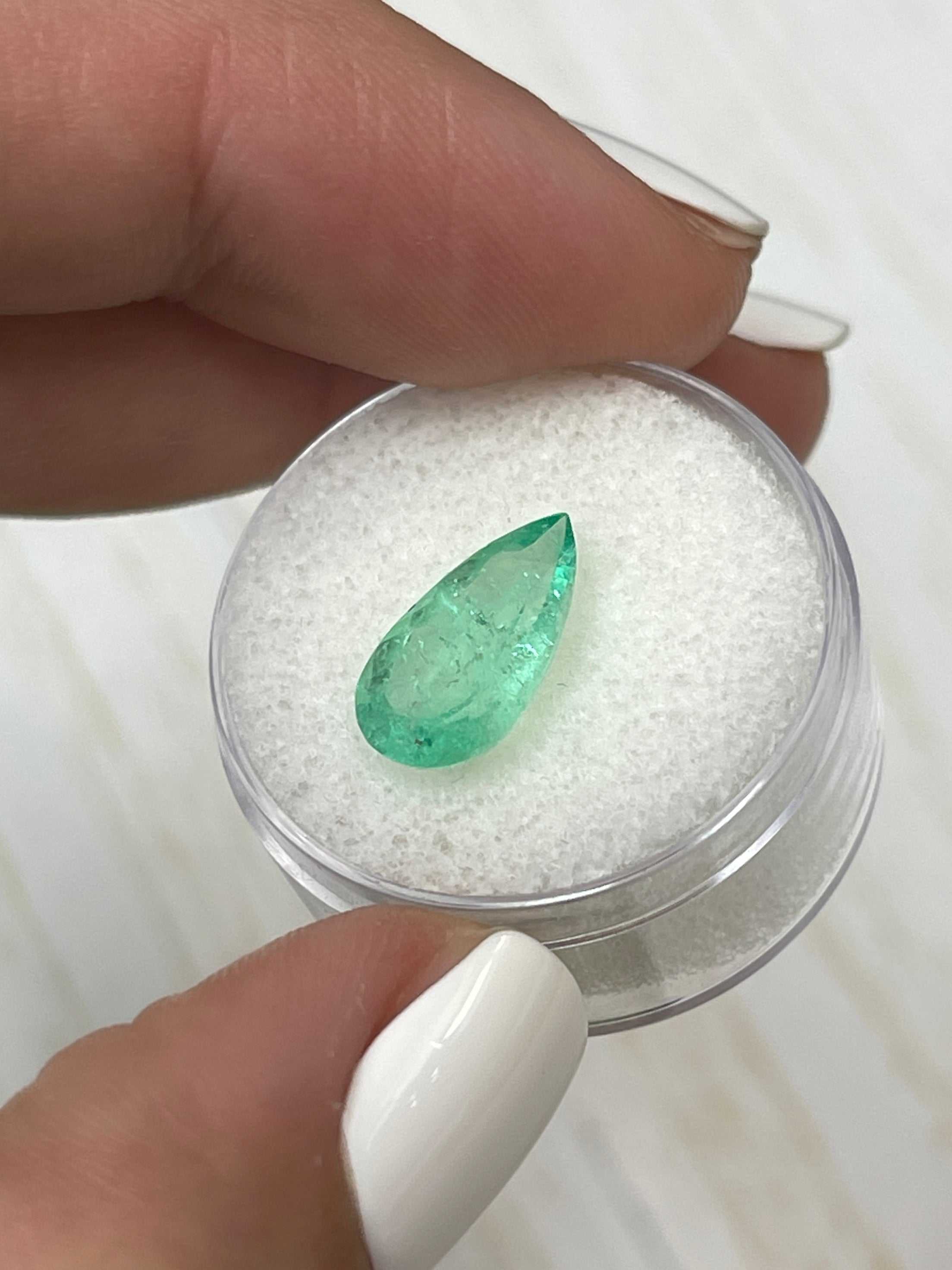 2.76 carat elongated green Colombian emerald in pear cut, showcasing rich color and clarity against a neutral background.