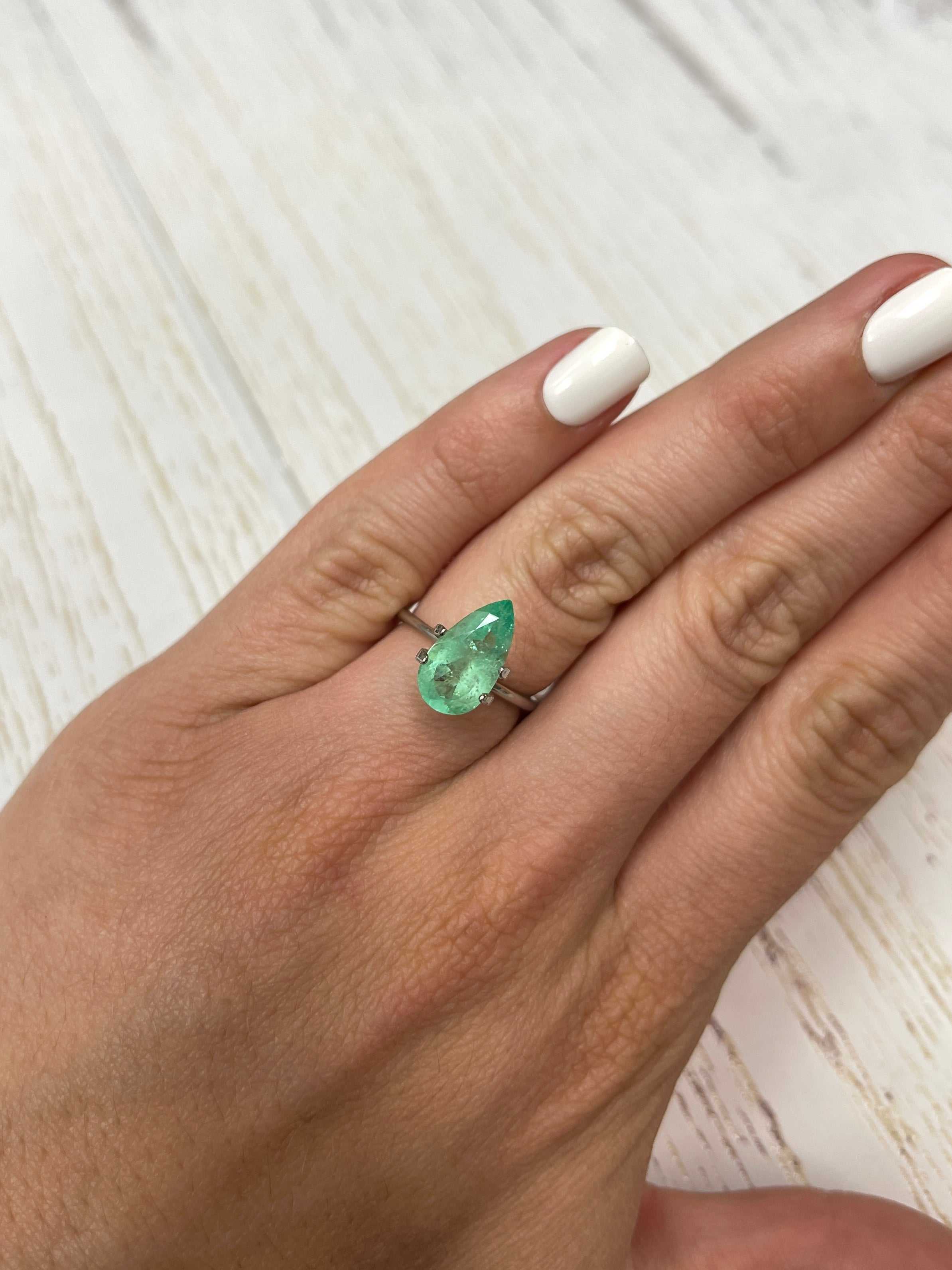 2.76 carat elongated green Colombian emerald in a pear cut, showcasing vibrant color and clarity against a neutral background.