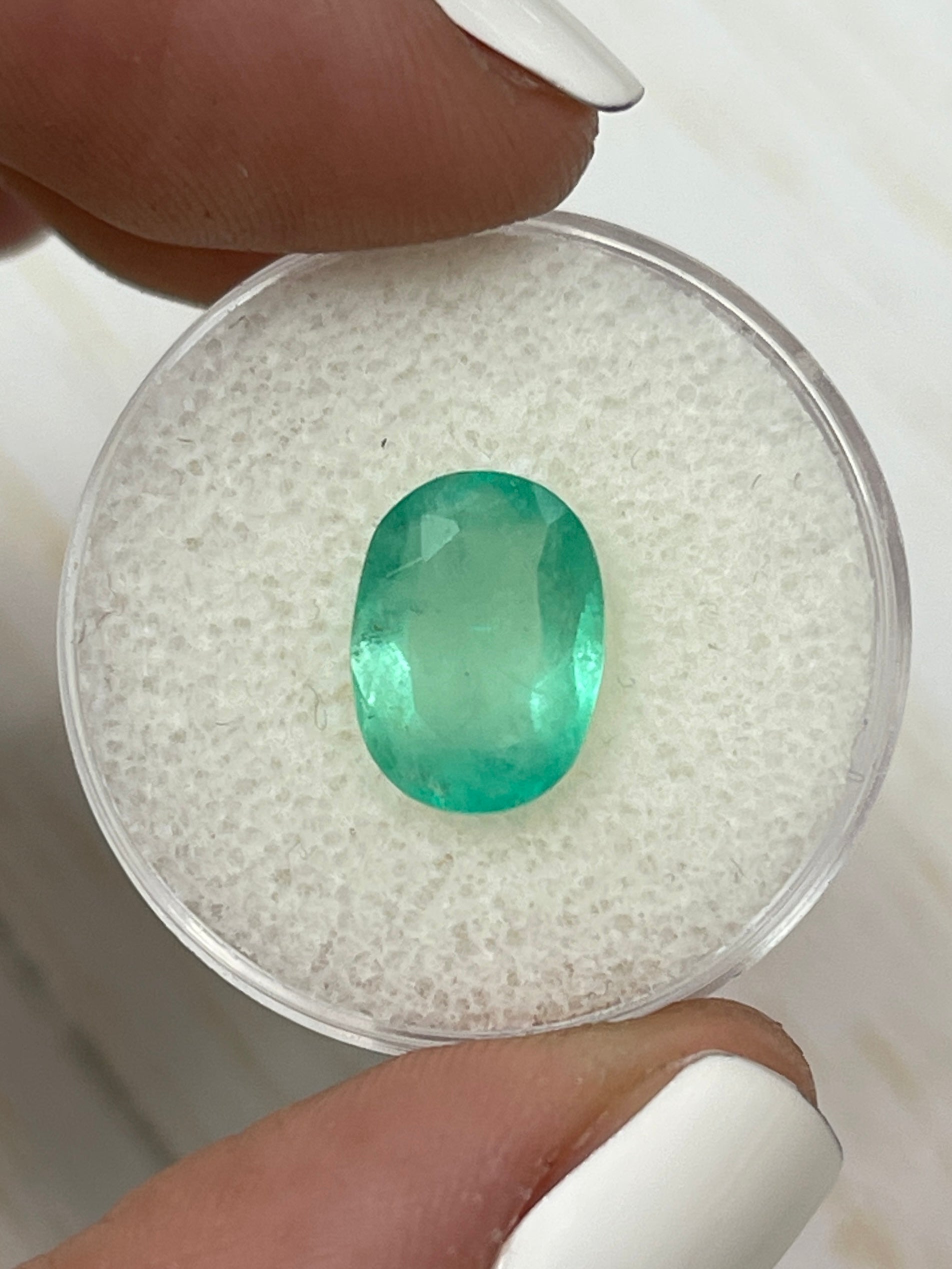 Oval cut 2.90 carat pastel mint green natural Colombian emerald from JR Colombian Emeralds, loose gemstone on a neutral background.