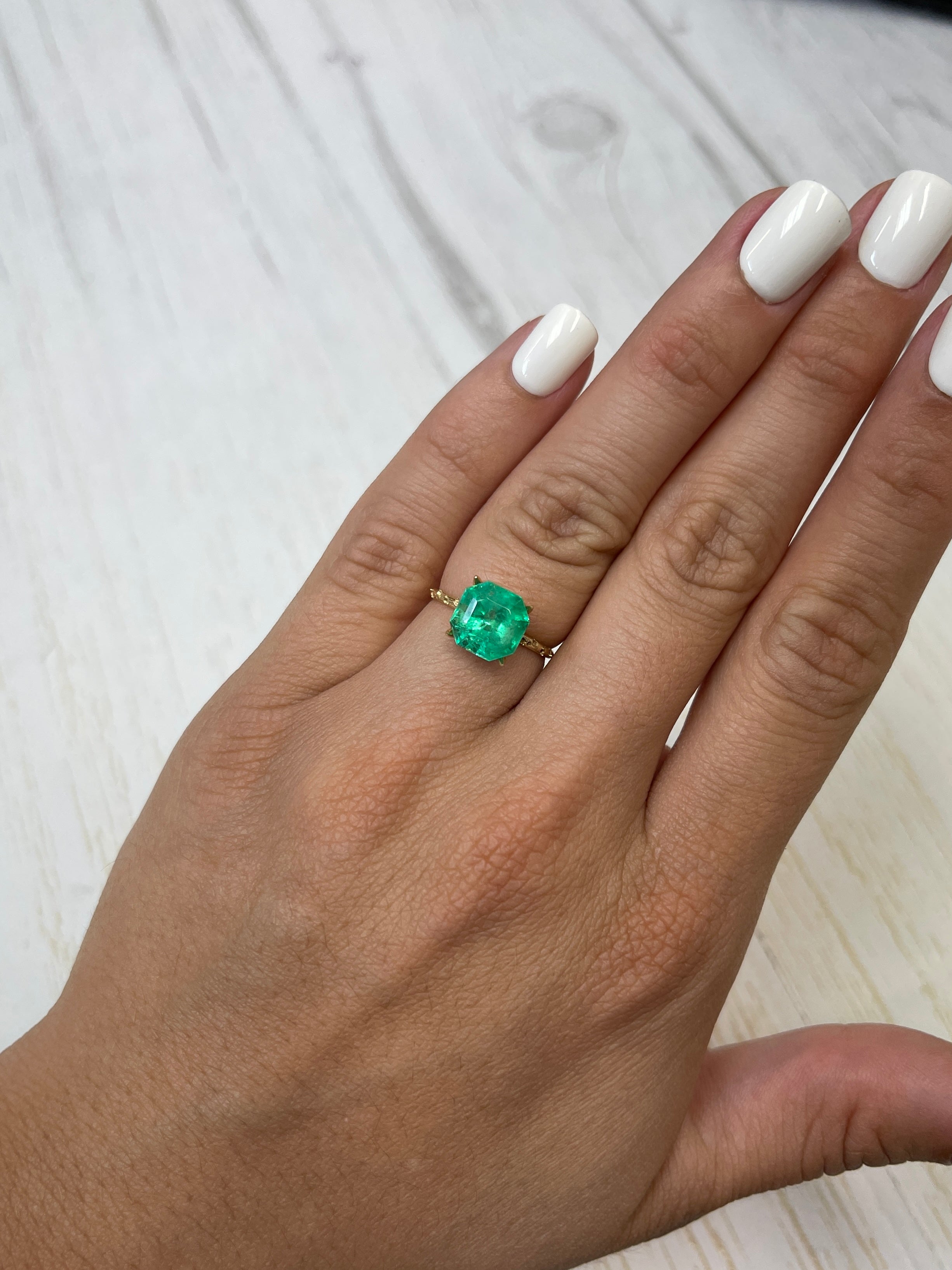 Luminous 3.68-carat natural Colombian Emerald loose Asscher cut with clipped corners, displayed on a neutral background.