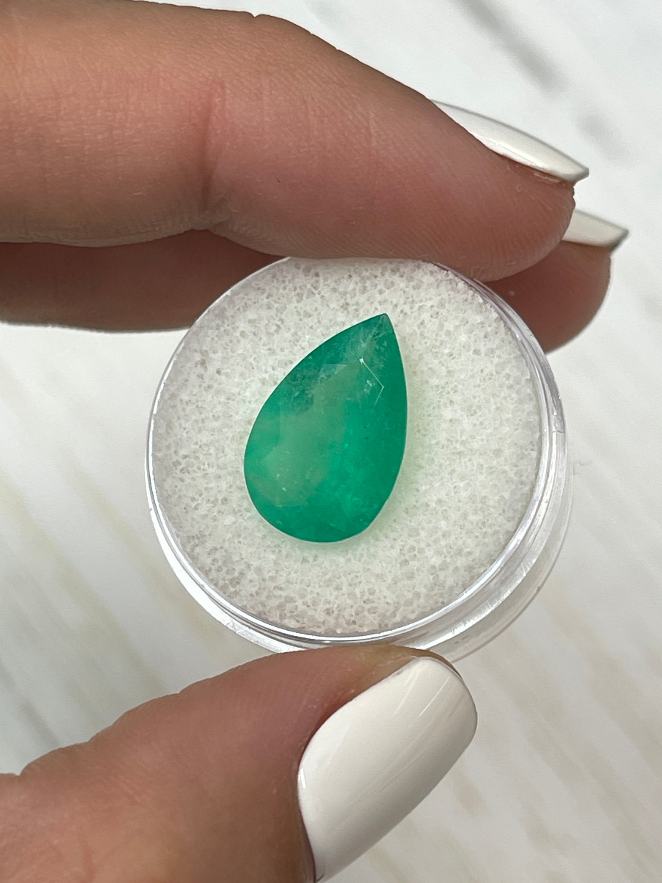 5.63 carat apple green natural Colombian emerald loose gemstone with pear cut, displayed by JR Colombian Emeralds.