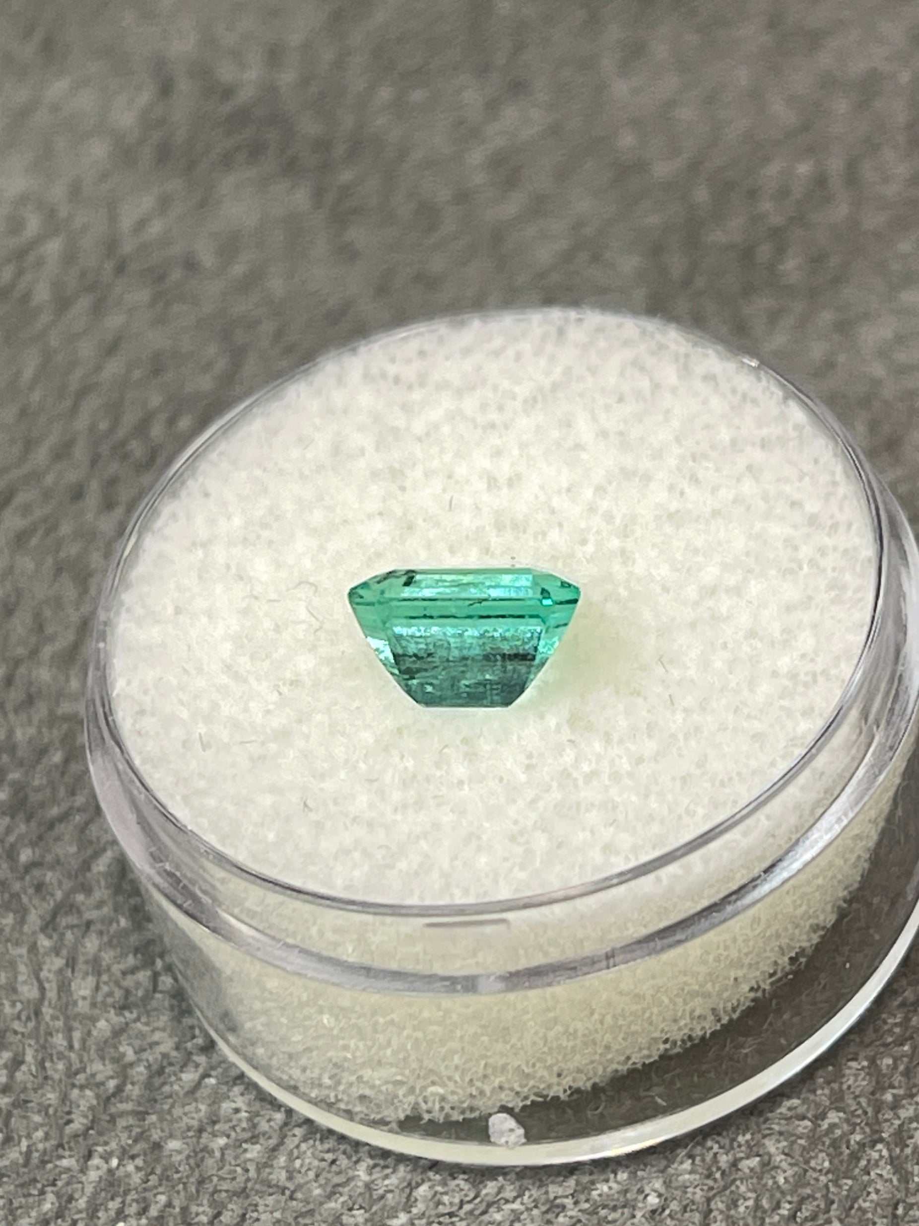 1.69 Carat bright bluish green Colombian emerald loose gemstone in emerald cut, displayed with 18k yellow gold solitaire ring setting.