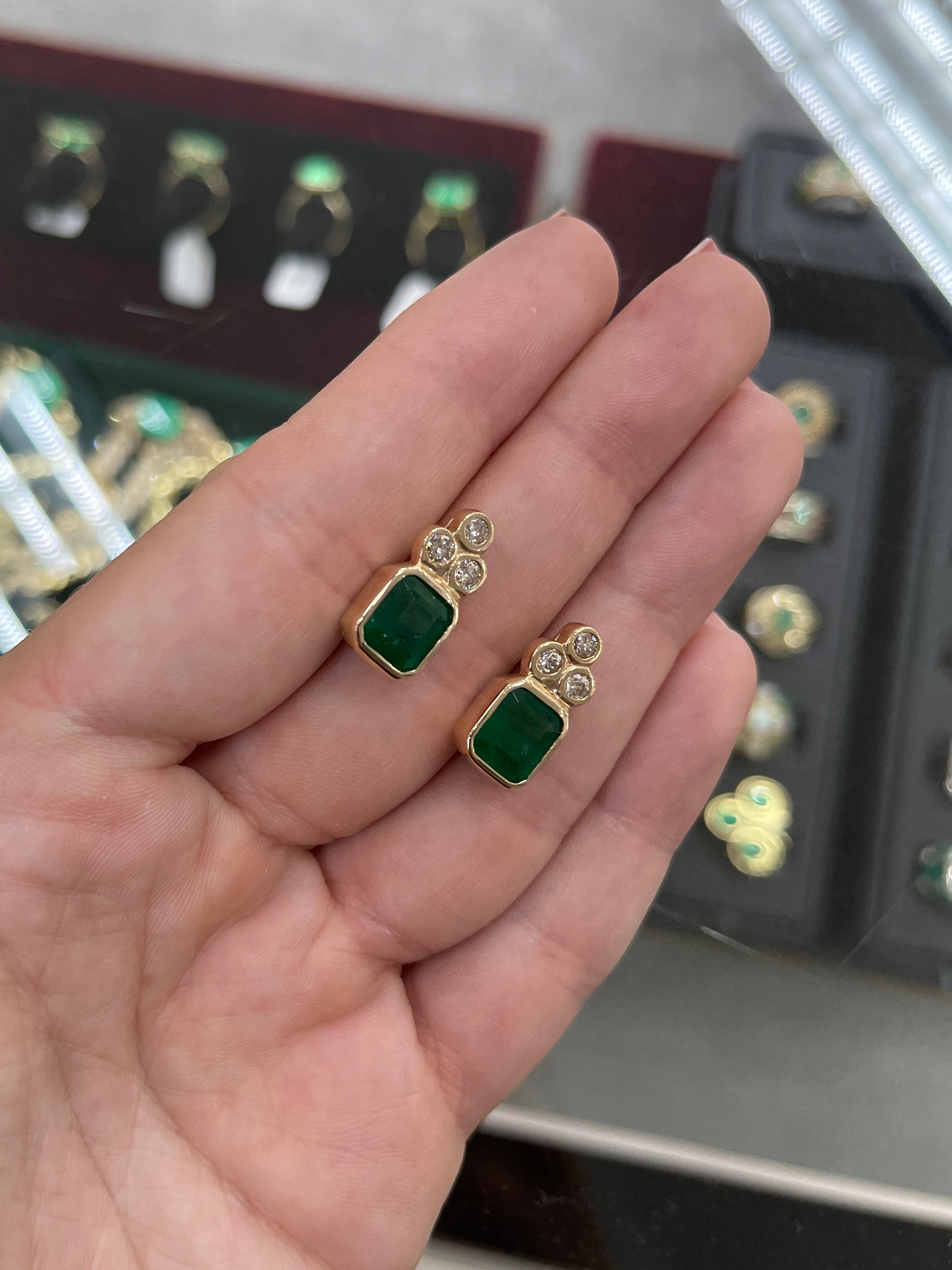 Natural dark forest green emerald cut earrings with diamond accents in 14K gold, featuring bezel setting from JR Colombian Emeralds.