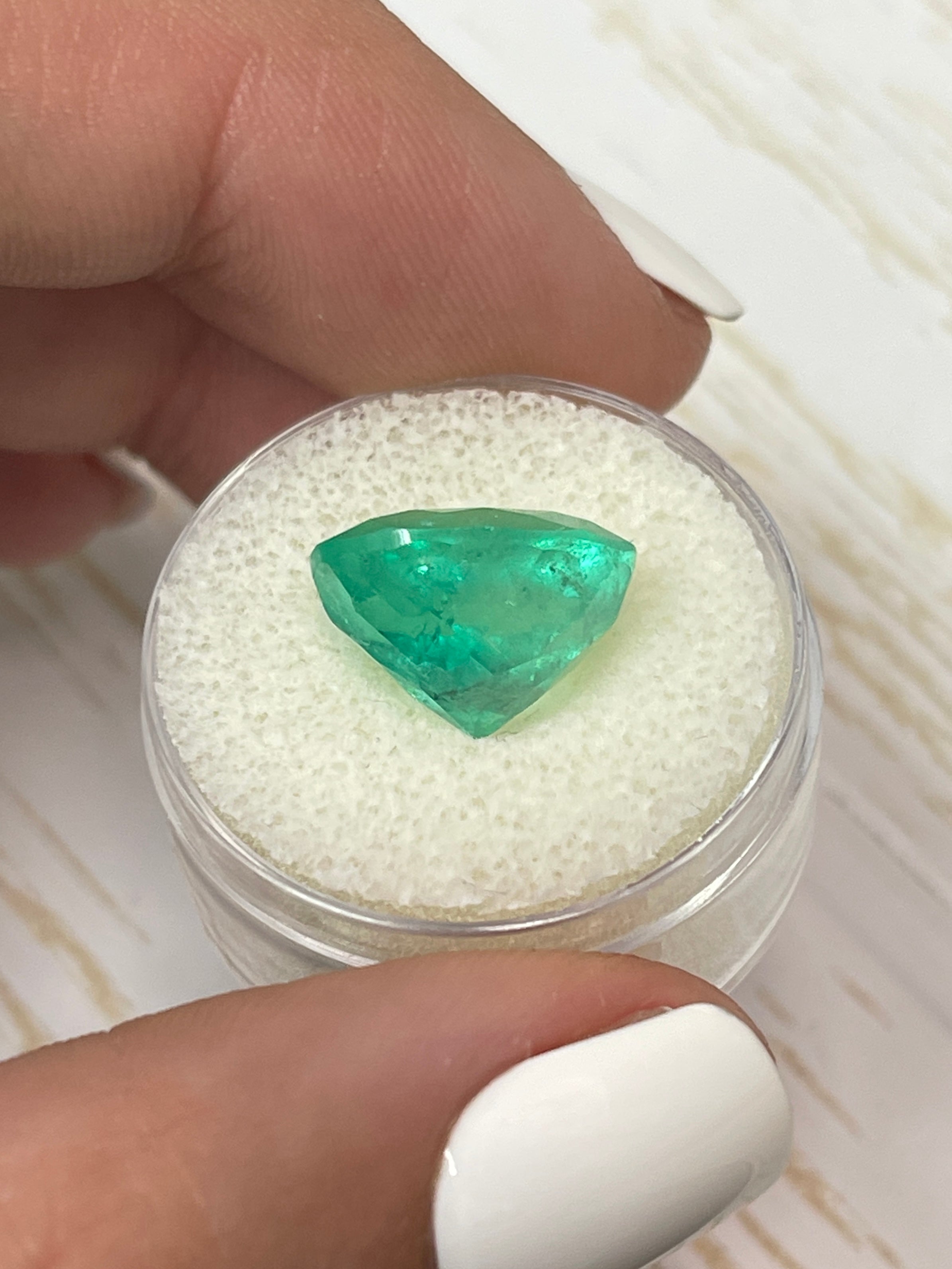 7.80 carat medium yellowish green natural Colombian emerald loose oval cut gemstone with vibrant color and clarity.