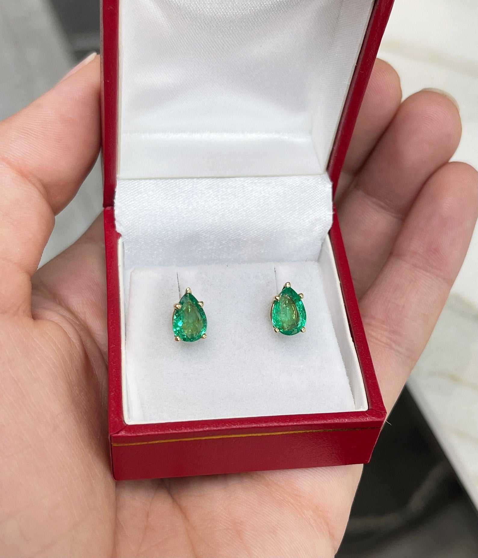 Natural pear-cut emerald stud earrings in rich green, set in 14K yellow gold, from JR Colombian Emeralds.