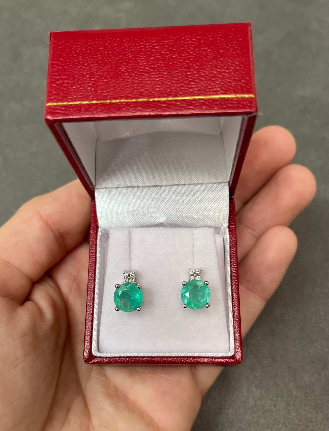 Rich blue-green Colombian emerald and diamond accent stud earrings in 14K gold, featuring round gemstones and stacked design.