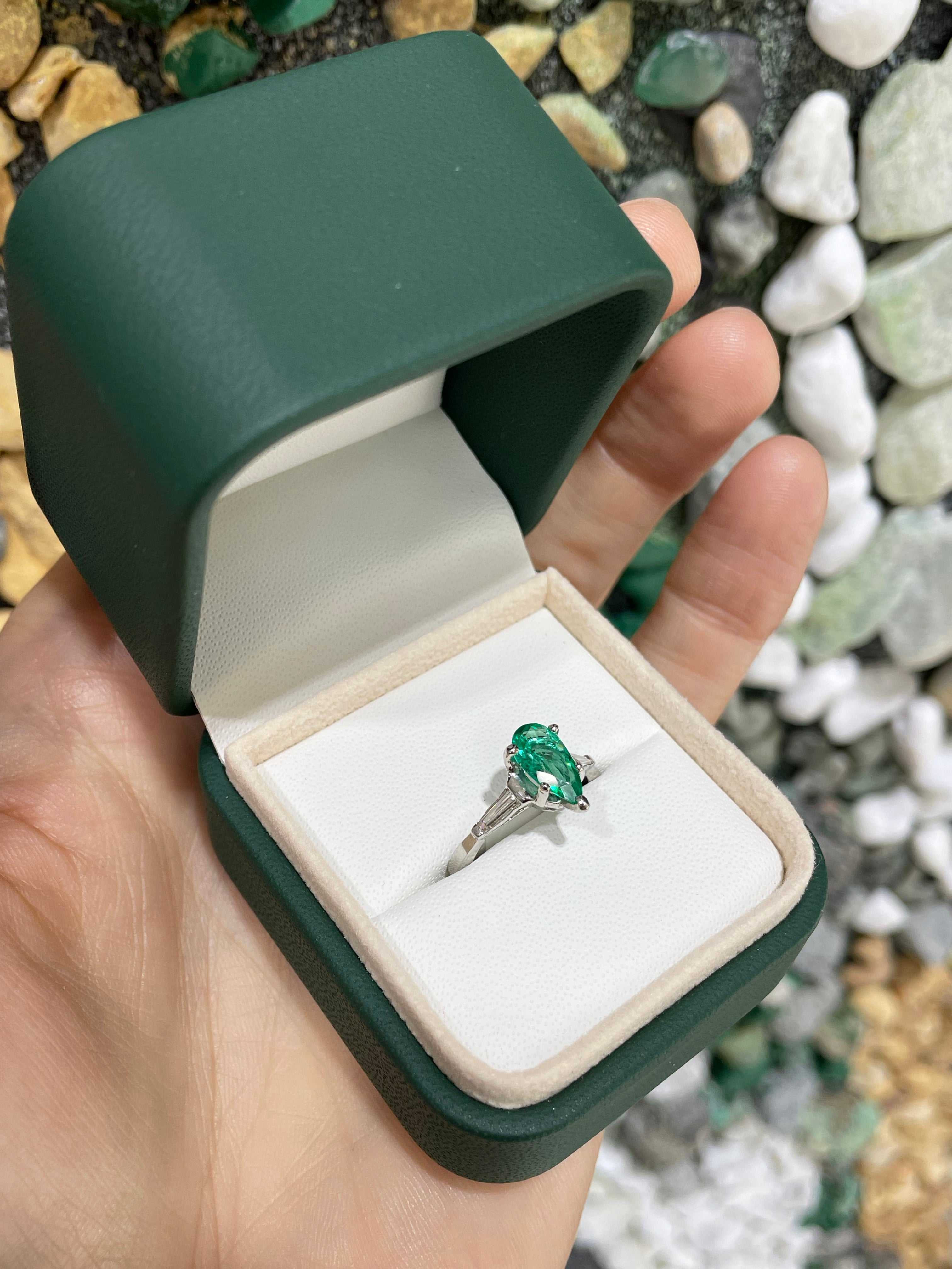 Elegant engagement ring featuring a 1.49tcw pear-cut Colombian emerald with tapered baguette diamonds in 18K gold.