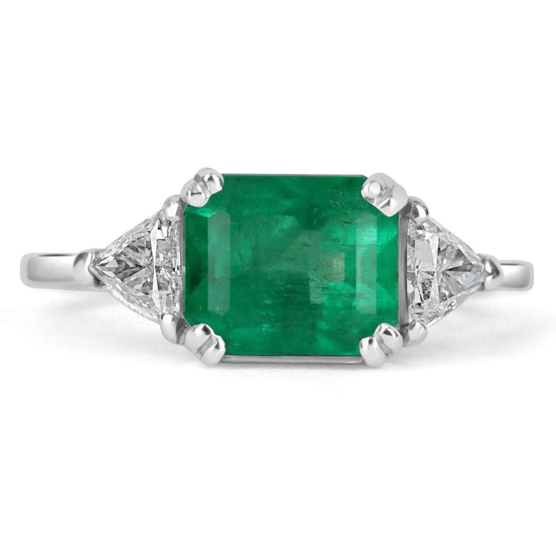 Three-stone engagement ring with emerald cut Colombian emeralds and trillion diamonds in 18K gold, by JR Colombian Emeralds.
