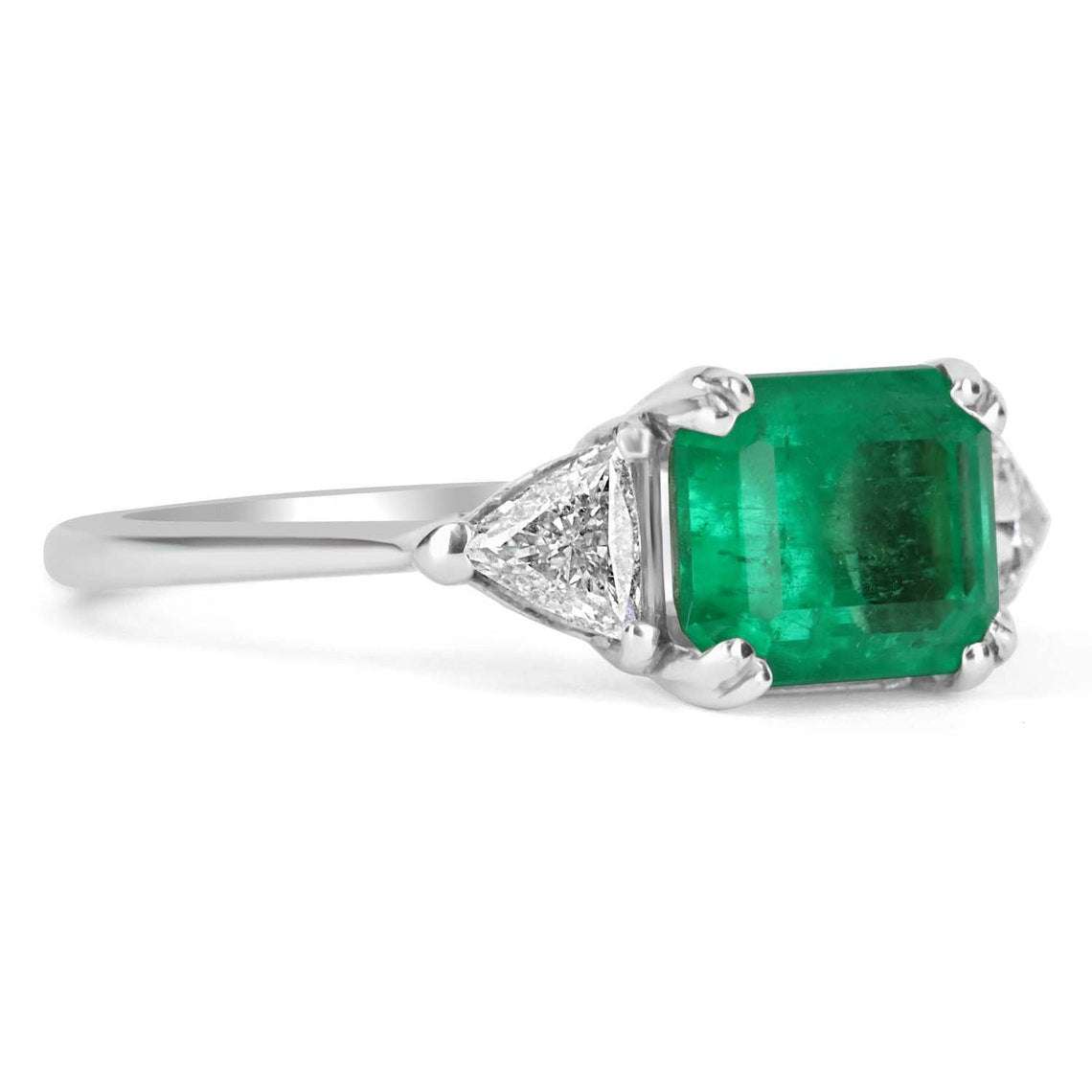 Three stone engagement ring featuring emerald cut Colombian emerald and trillion diamonds in 18K gold by JR Colombian Emeralds.