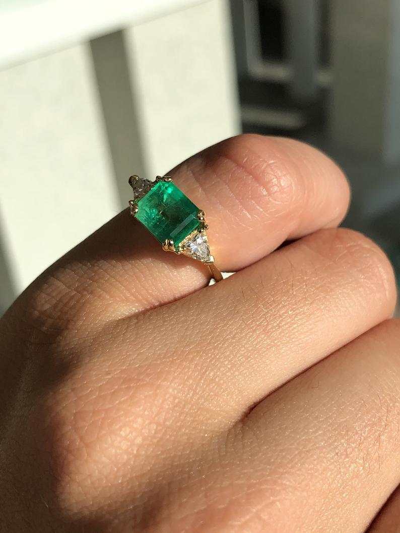 Three-stone engagement ring with emerald cut Colombian emeralds and trillion diamonds in 18K gold, by JR Colombian Emeralds.