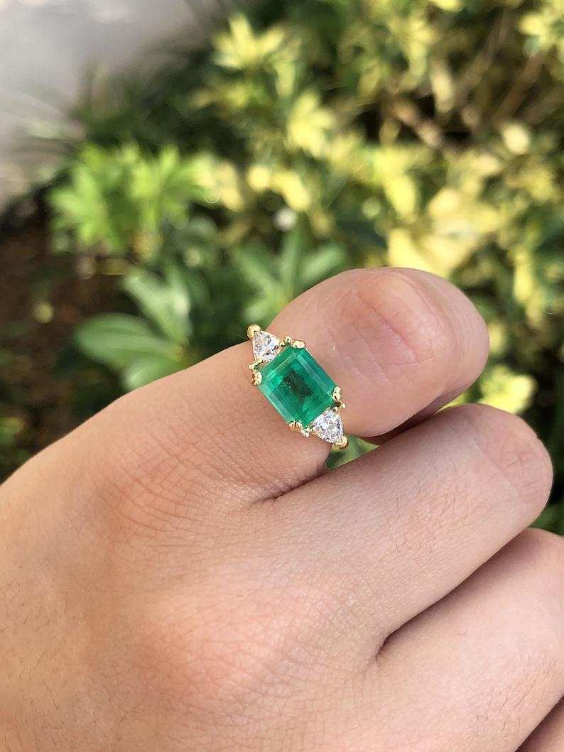 Three-stone engagement ring with emerald cut Colombian emeralds and trillion diamonds in 18K gold by JR Colombian Emeralds.