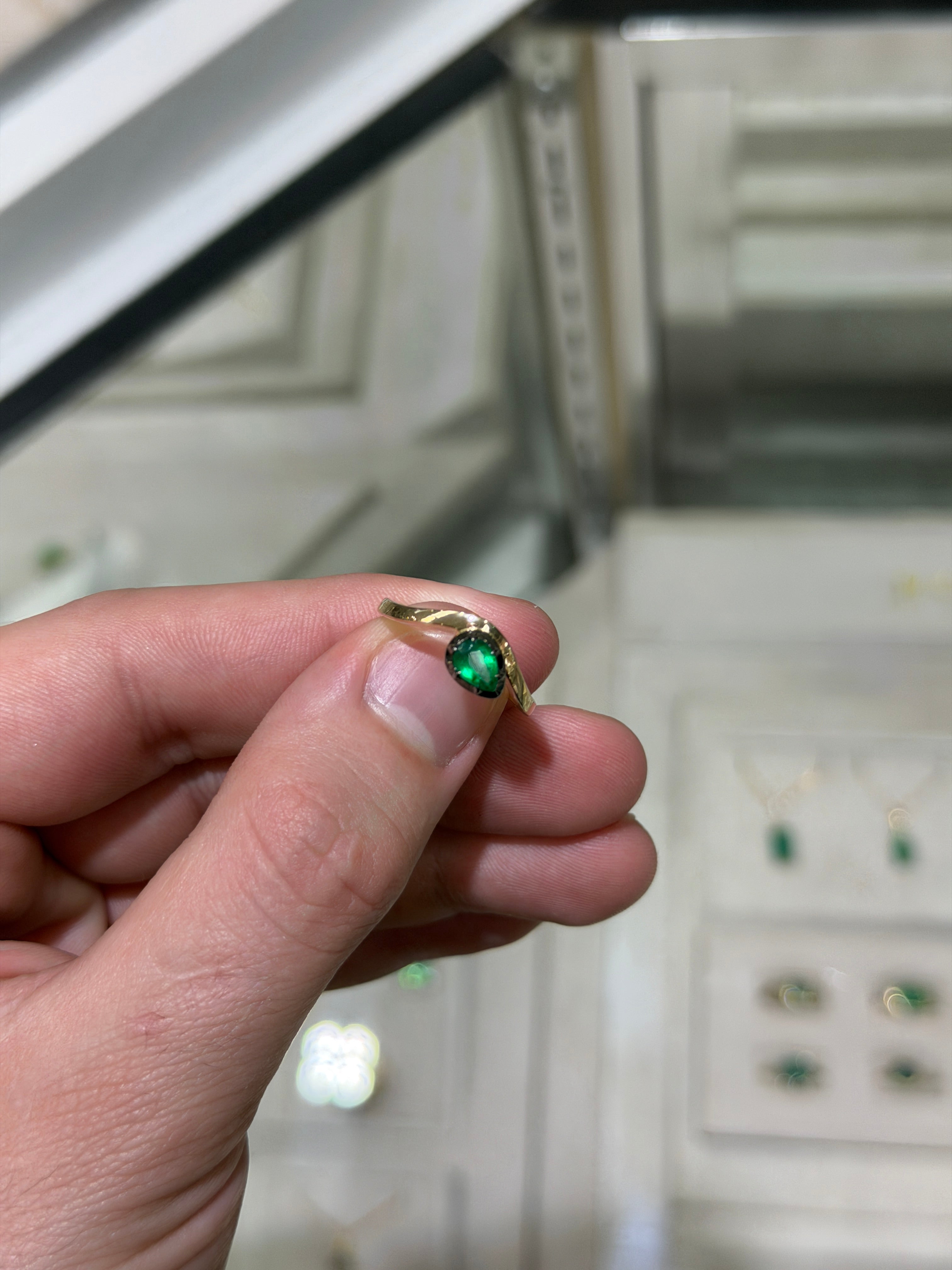 14K gold emerald solitaire ring with a pear-cut green emerald and black rhodium accents, featuring a 0.46ct gemstone.