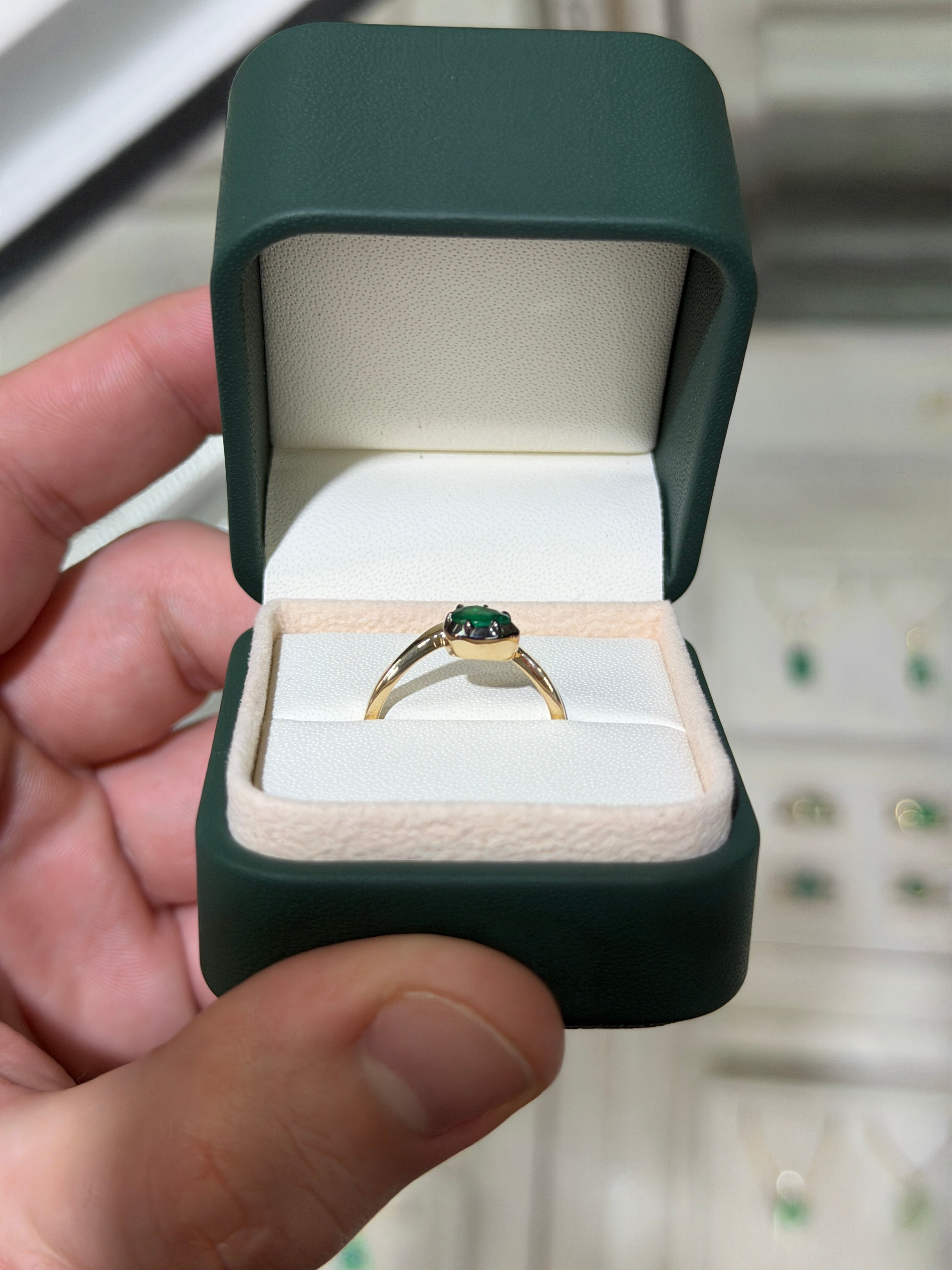 14K gold emerald solitaire ring with a pear-shaped green emerald and black rhodium accents, showcasing elegant jewelry craftsmanship.