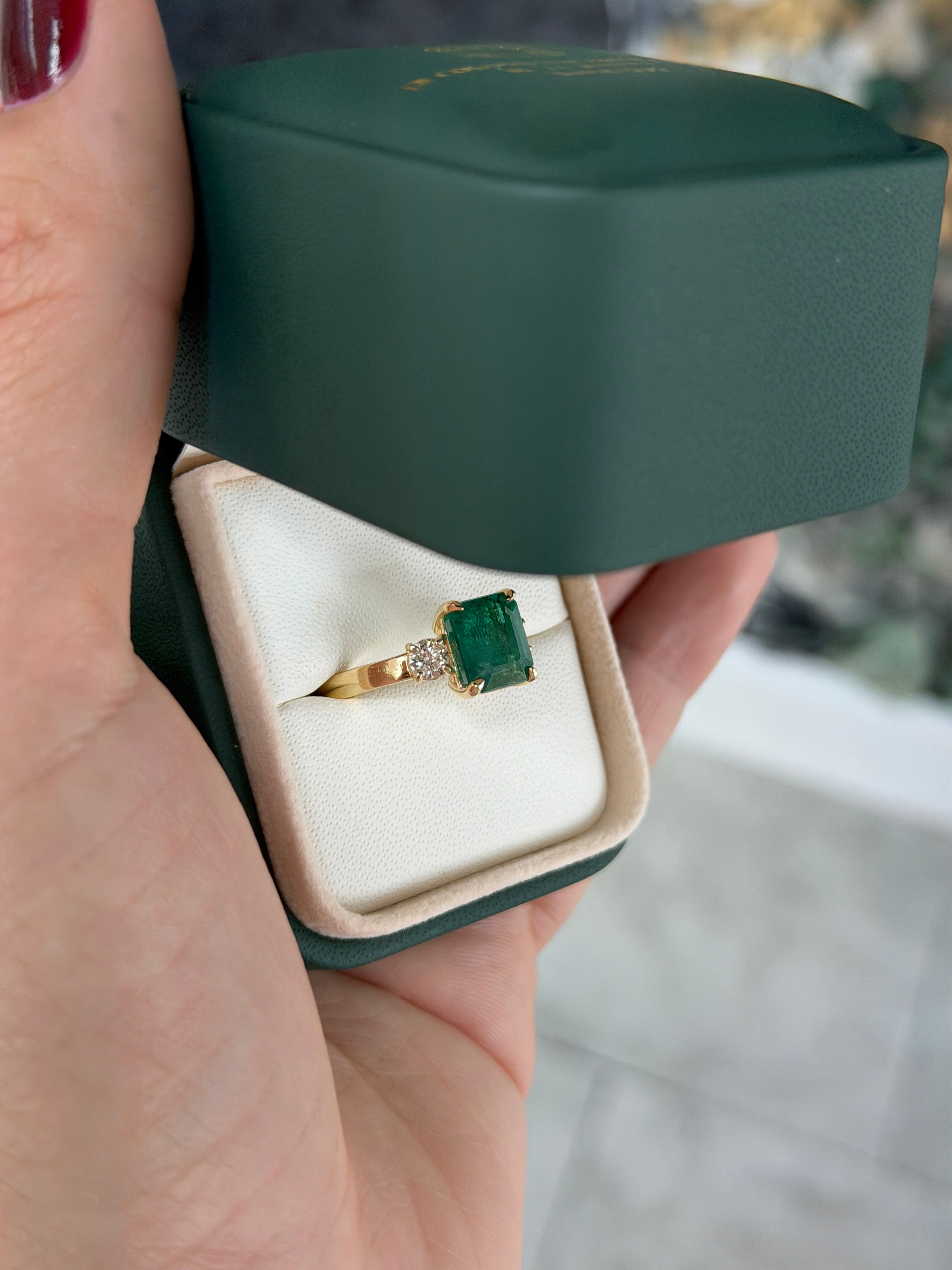 14K gold Zambian emerald cut three-stone engagement ring with round diamond side stones by JR Colombian Emeralds.