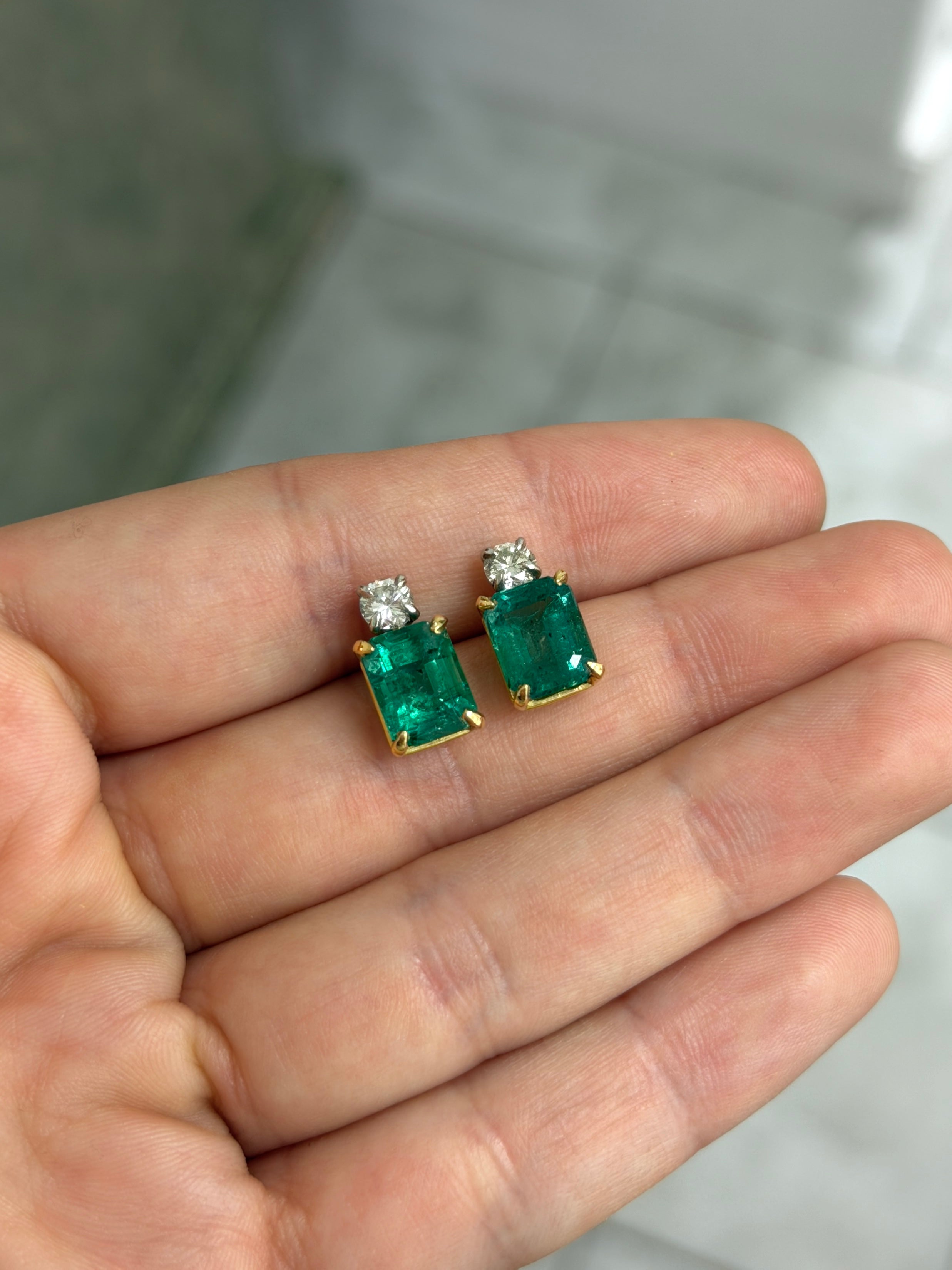 Colombian Emerald 18K two-tone earrings with 7.20tcw natural emerald-cut and round diamonds in vivid bluish-green hues.