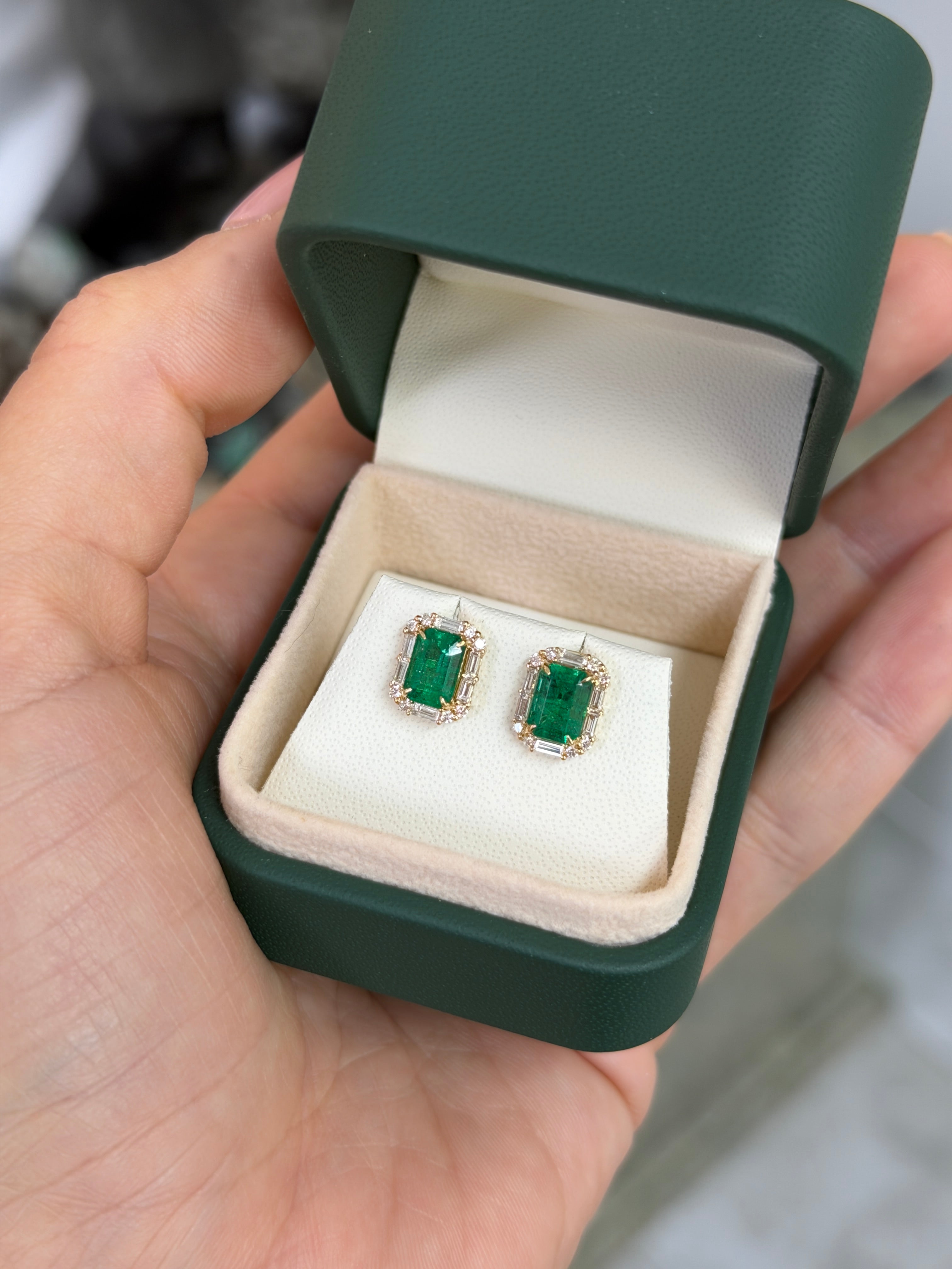 Elegant 18K gold stud earrings featuring rich green emeralds and baguette diamonds in a halo setting by JR Colombian Emeralds.