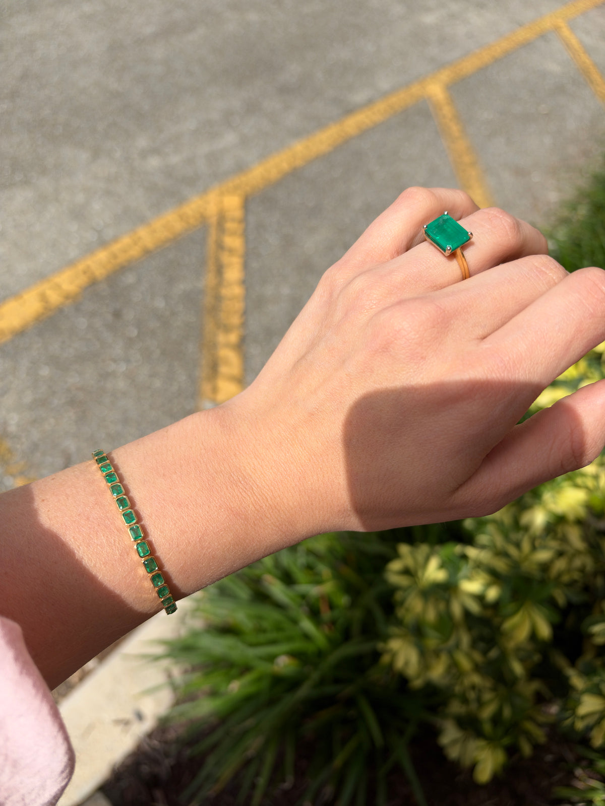 14K gold East to West bezel set emerald tennis bracelet with 6.69 carats total weight, featuring vibrant green Colombian emeralds.
