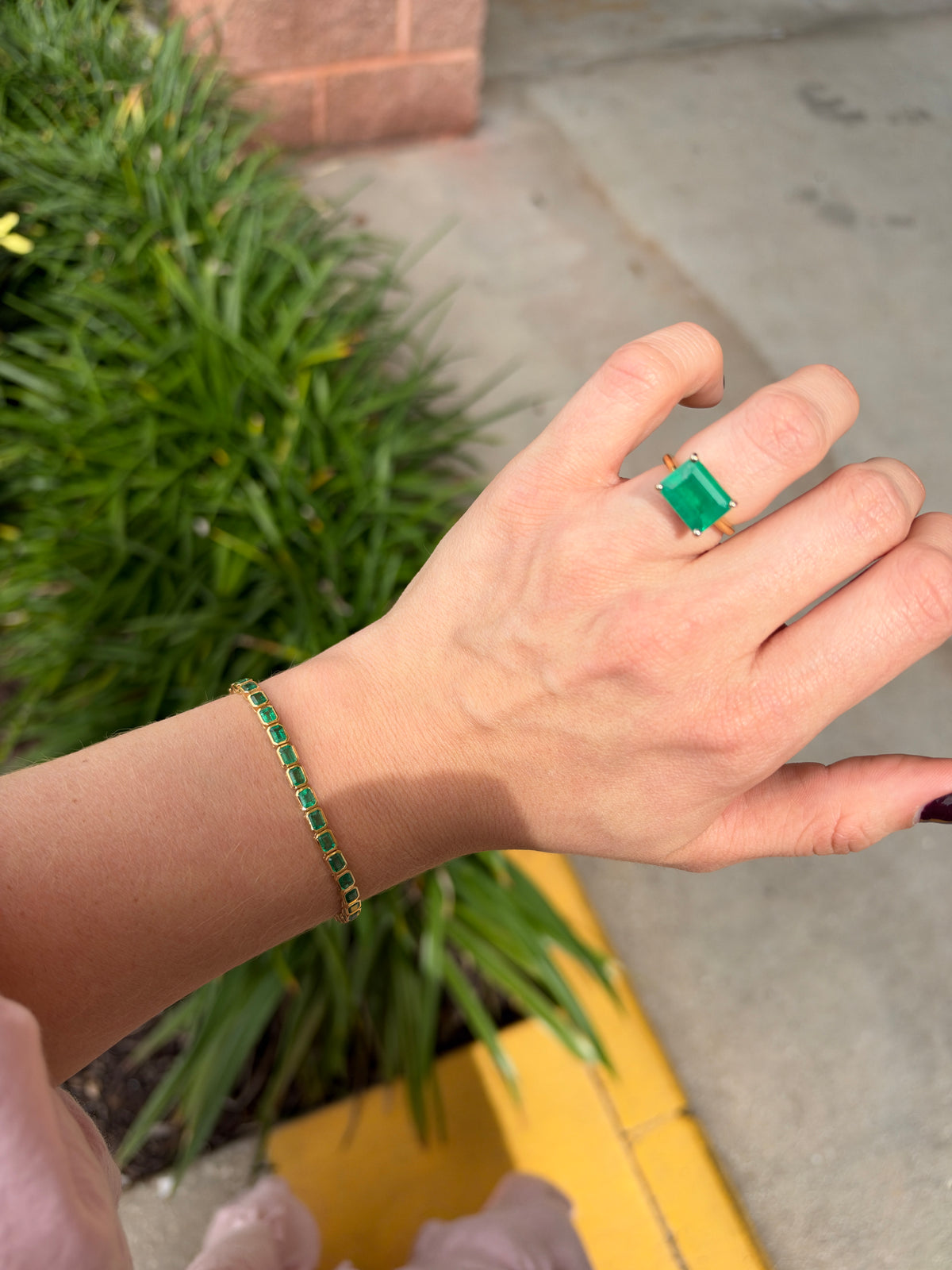14K gold emerald tennis bracelet with bezel-set 6.69 carats of Colombian emeralds, designed in an east-to-west style.