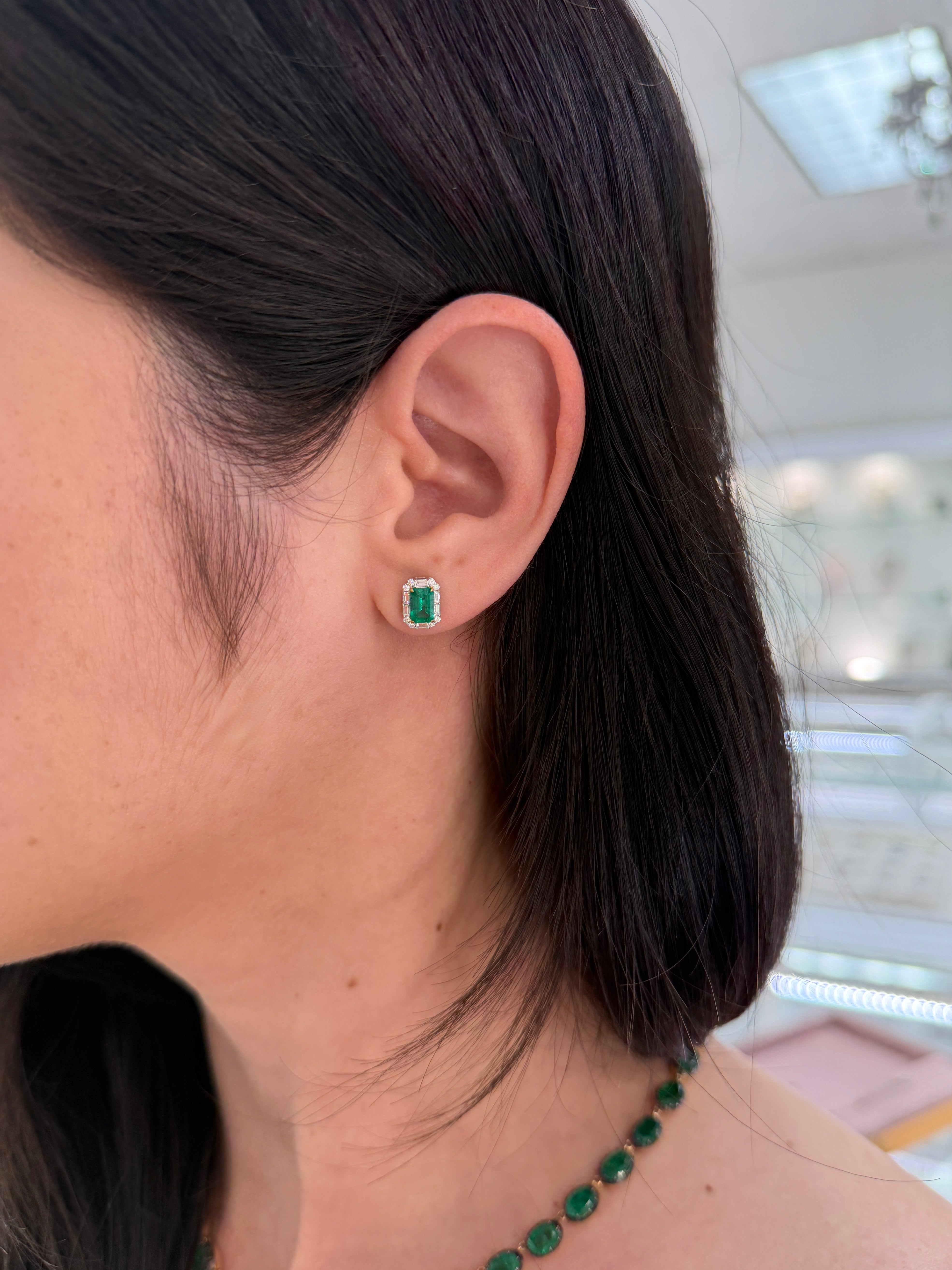 Natural emerald and baguette diamond halo stud earrings by JR Colombian Emeralds, 18K two-toned gold, featuring fine quality gemstones.
